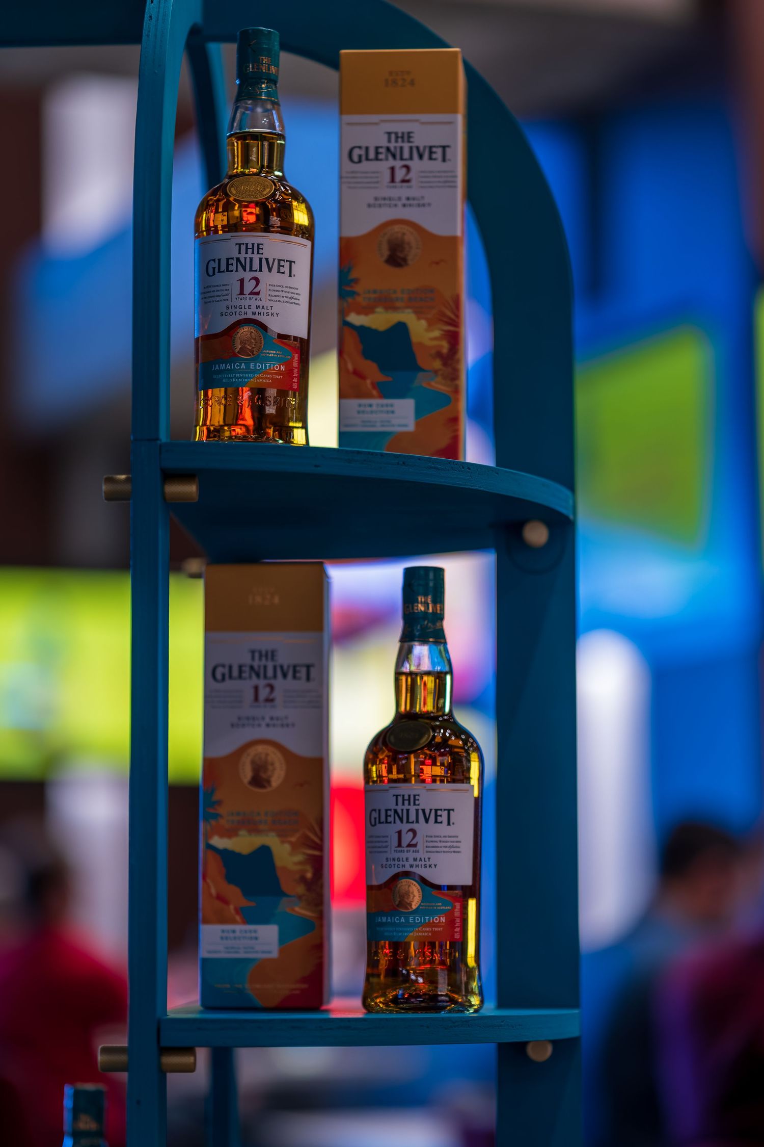 Display shelf showcasing Glenlivet whisky bottles with dramatic lighting and bokeh effects.