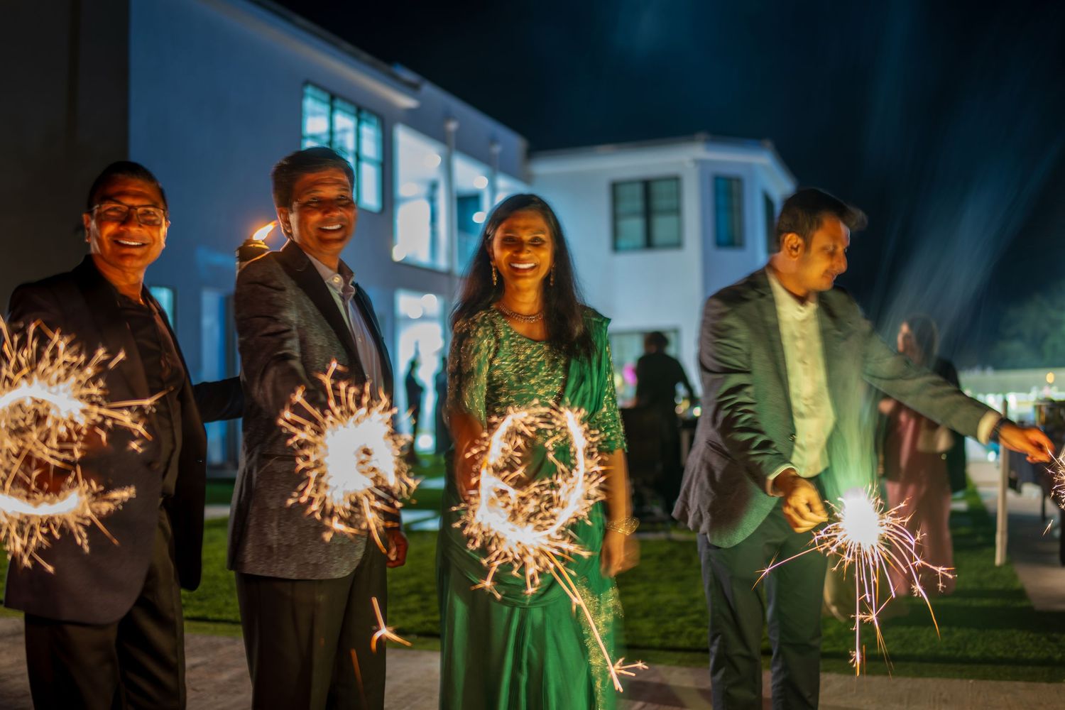 People hold sparklers creating a magical atmosphere against a dark blue evening sky.