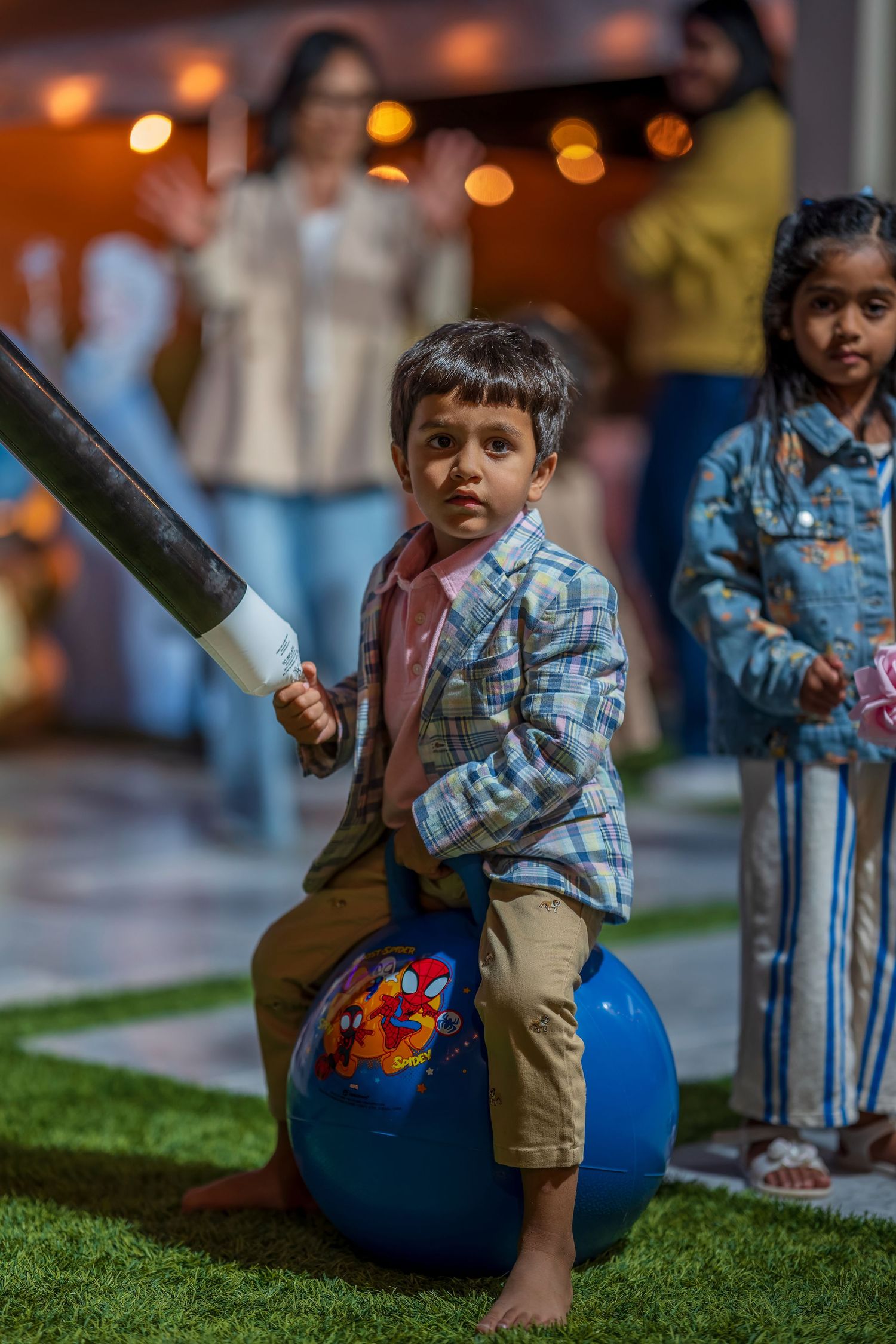 Children playing with blue exercise balls on artificial grass under evening lights.