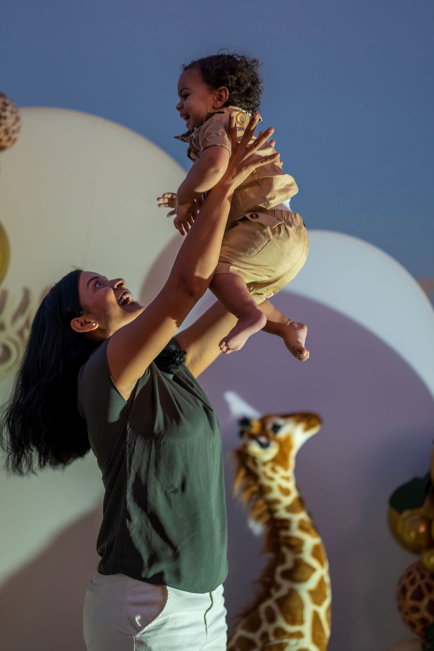 Candid celebration moment against a backdrop of safari decorations and festive balloons.