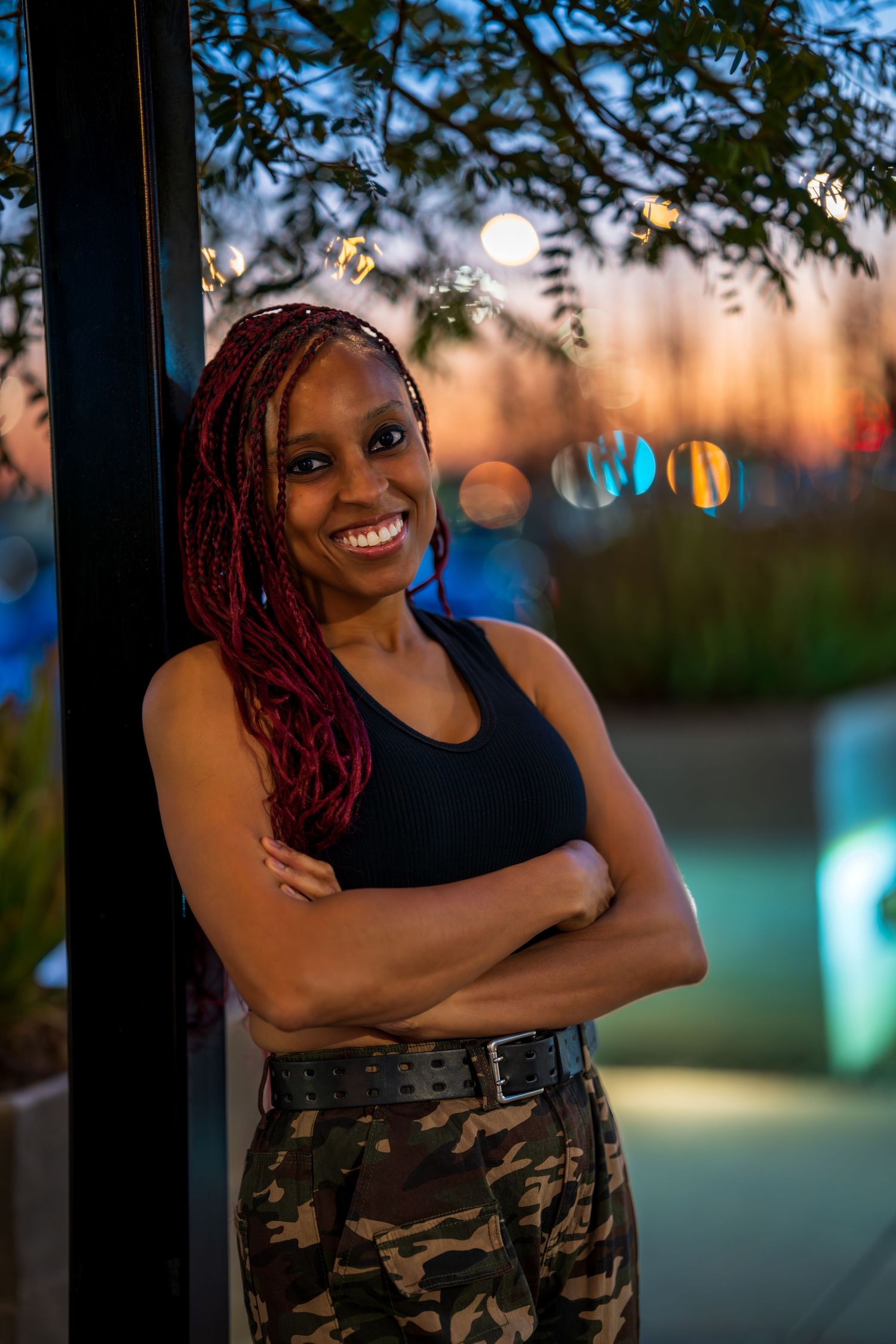 Evening portrait with camouflage pants and black top against colorful sunset.