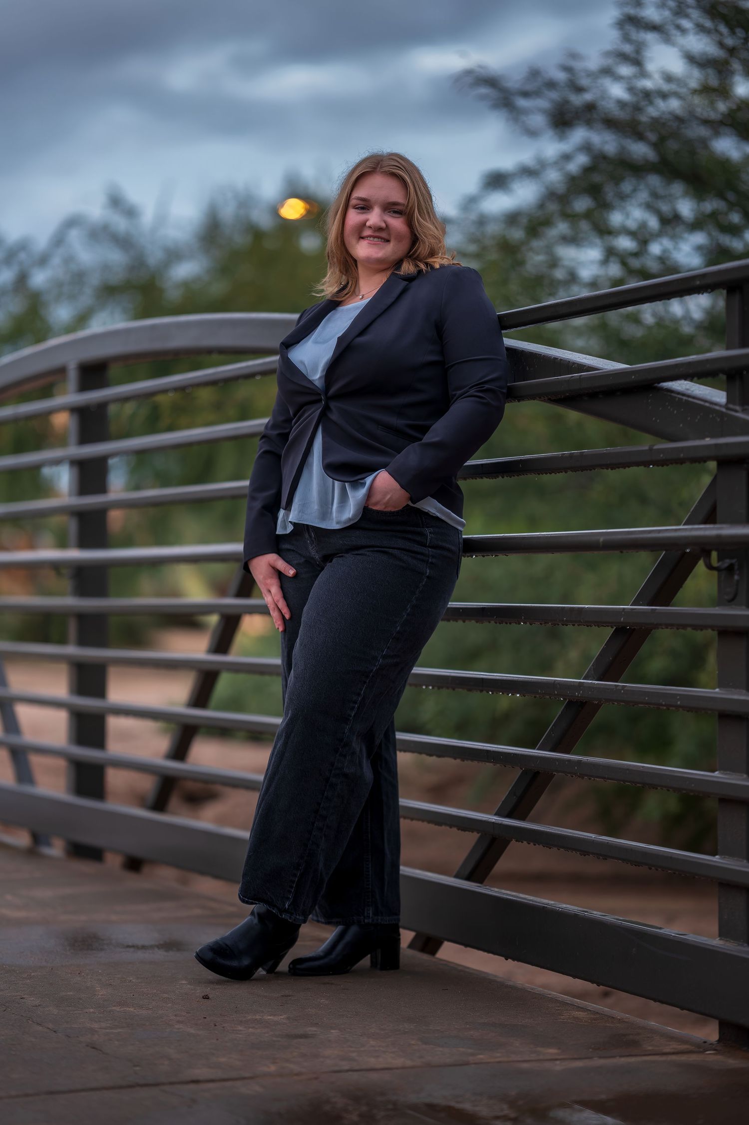 Professional portrait on bridge during dusk with architectural elements in background.