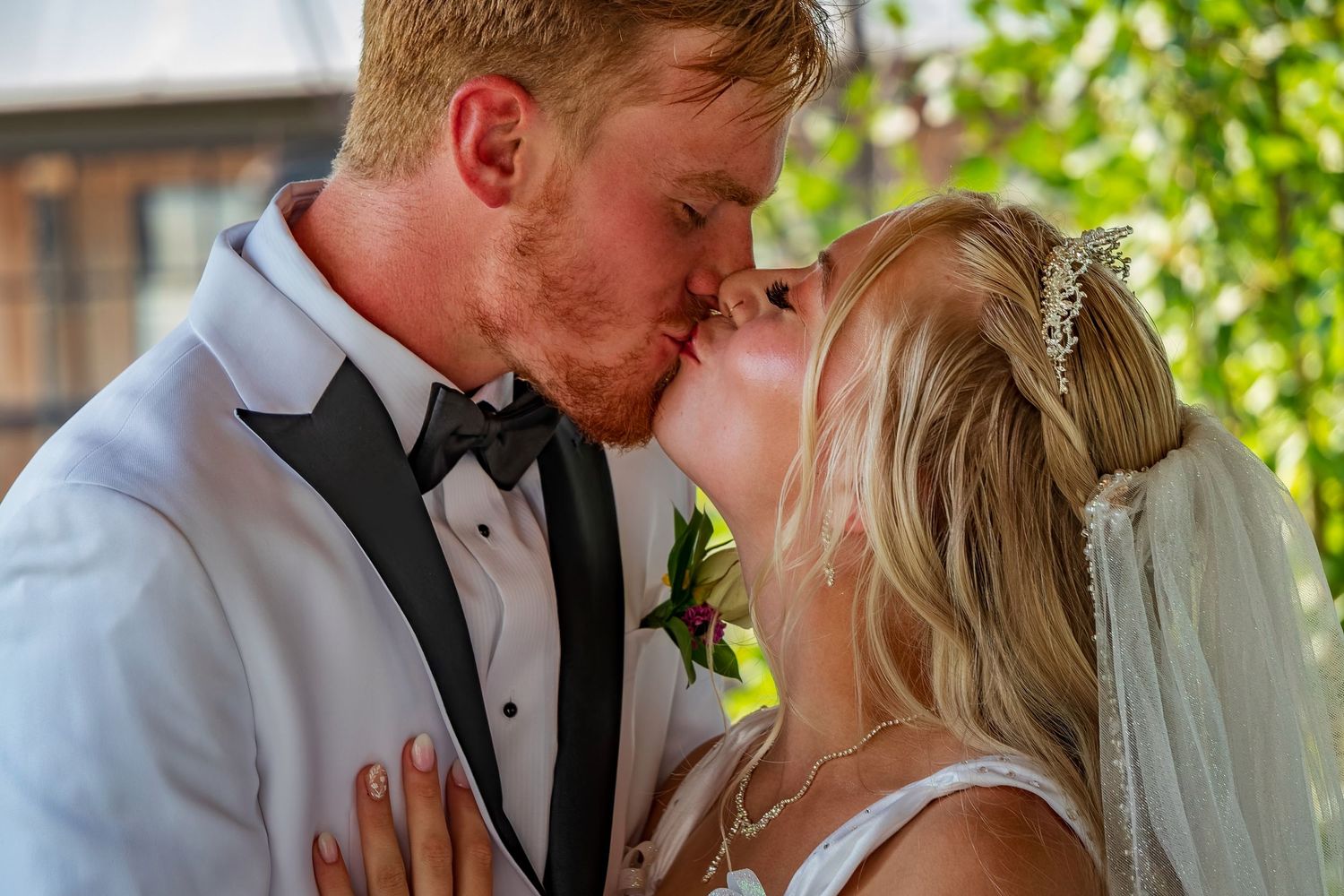 Romantic wedding kiss captured in a garden setting with natural lighting.