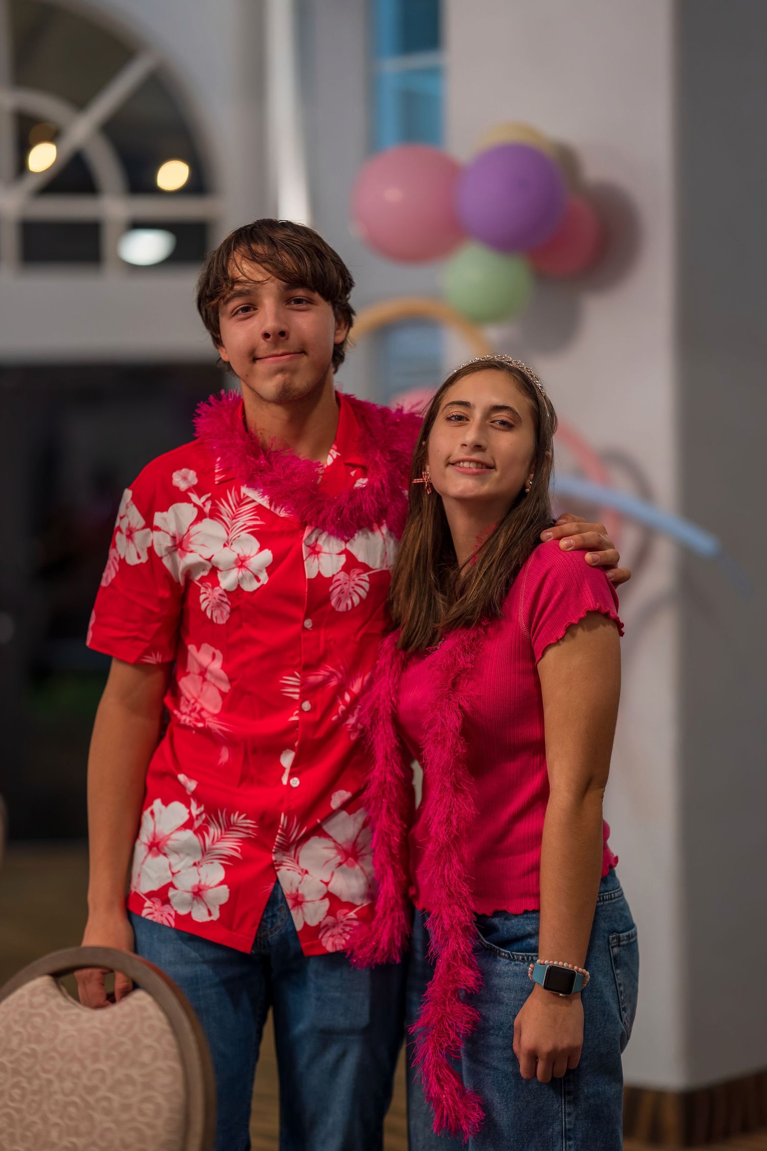 Partygoers in coordinated red and pink outfits with floral prints pose together.