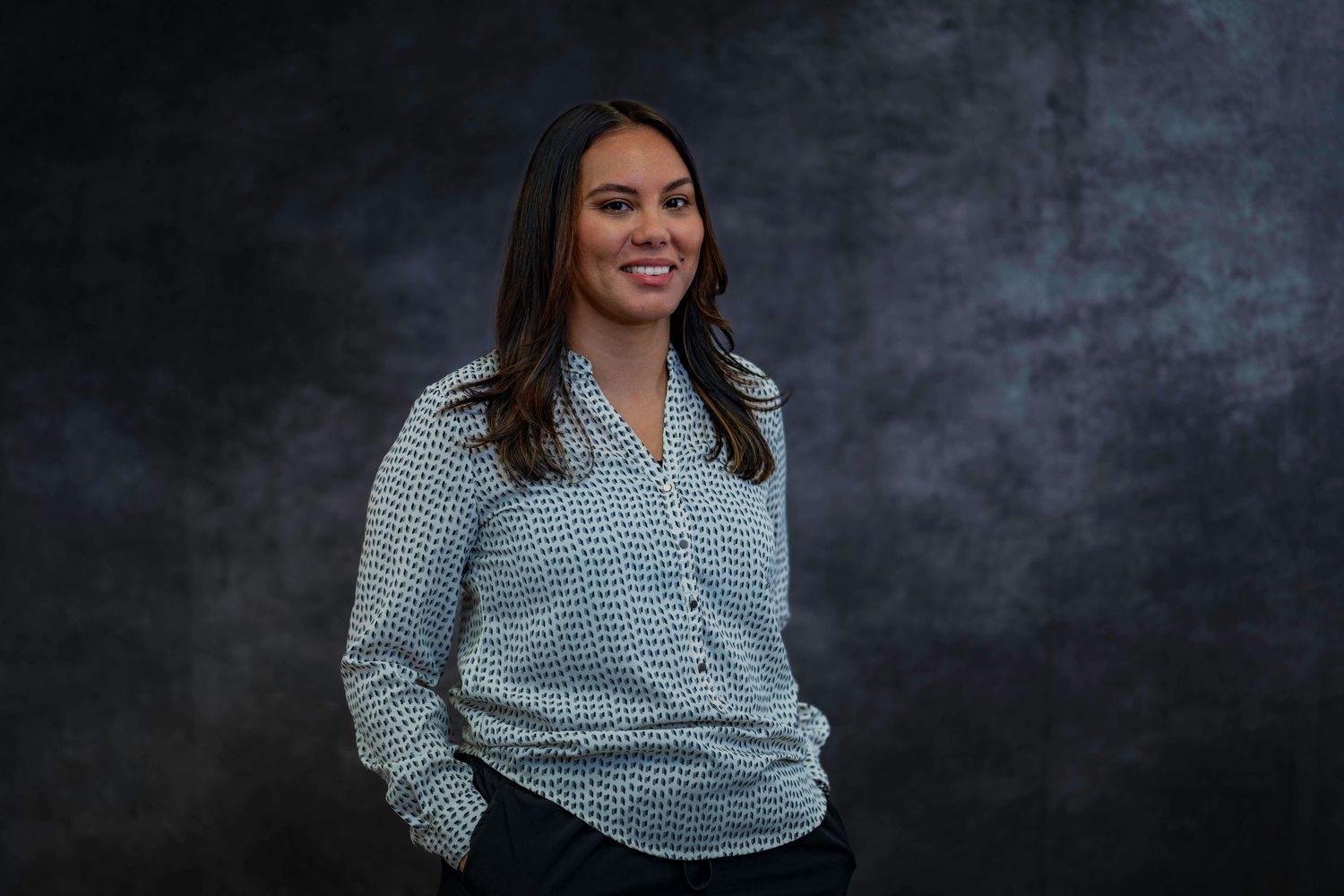 Person in geometric print blouse smiles during professional photoshoot.