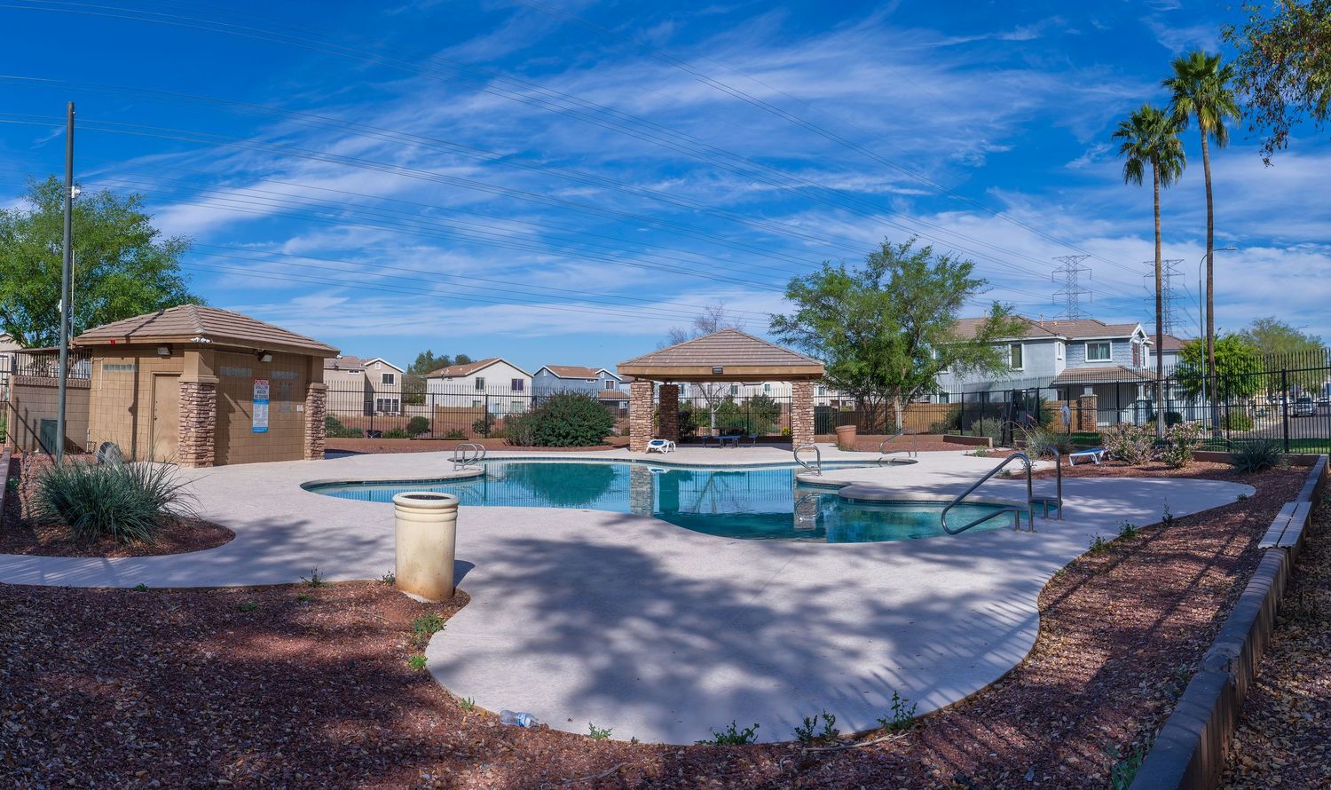 Community pool area with gazebo, palm trees, and blue skies in a sunny residential neighborhood.