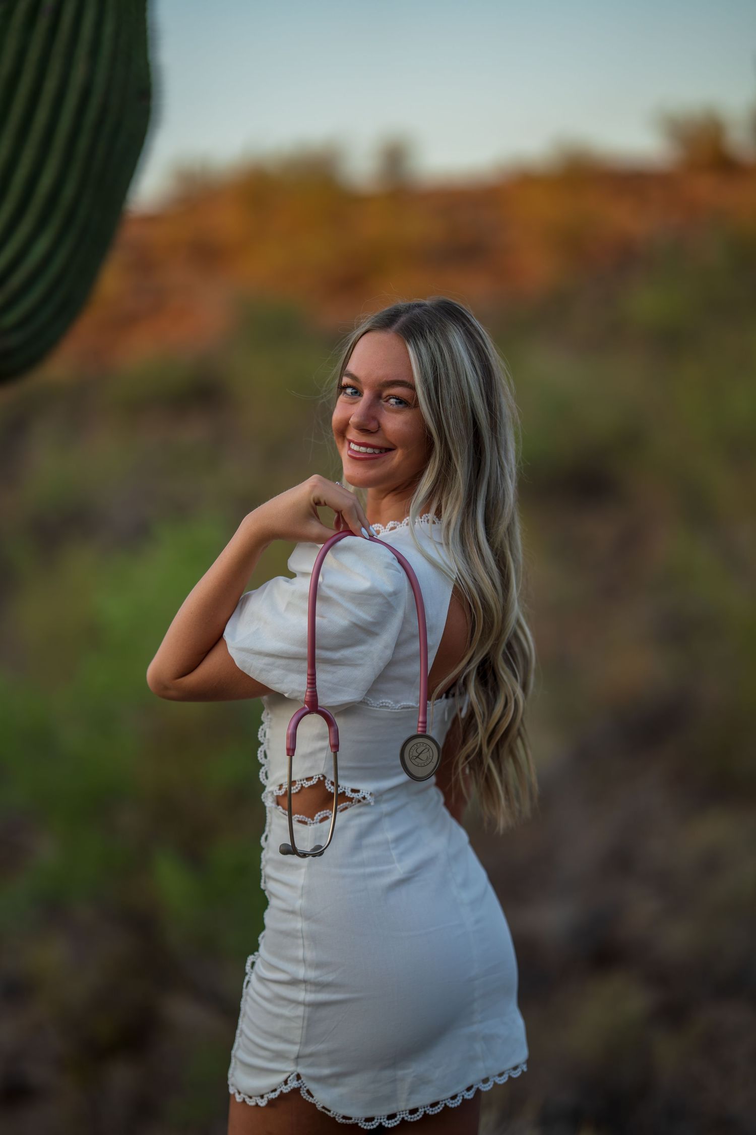 White dress with stethoscope accessory photographed in desert setting during sunset.