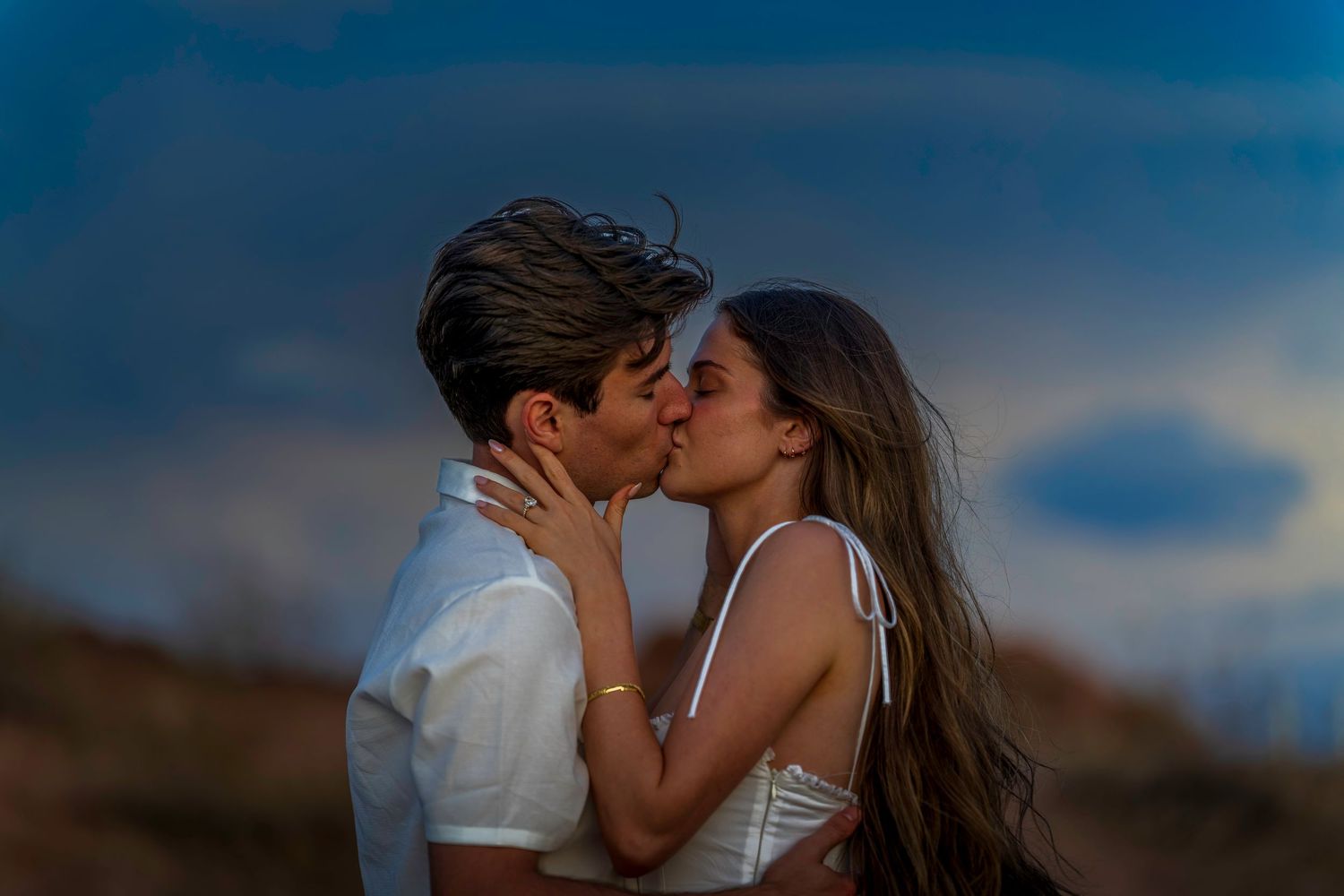 Couple in white clothing embracing during a sunset photoshoot.