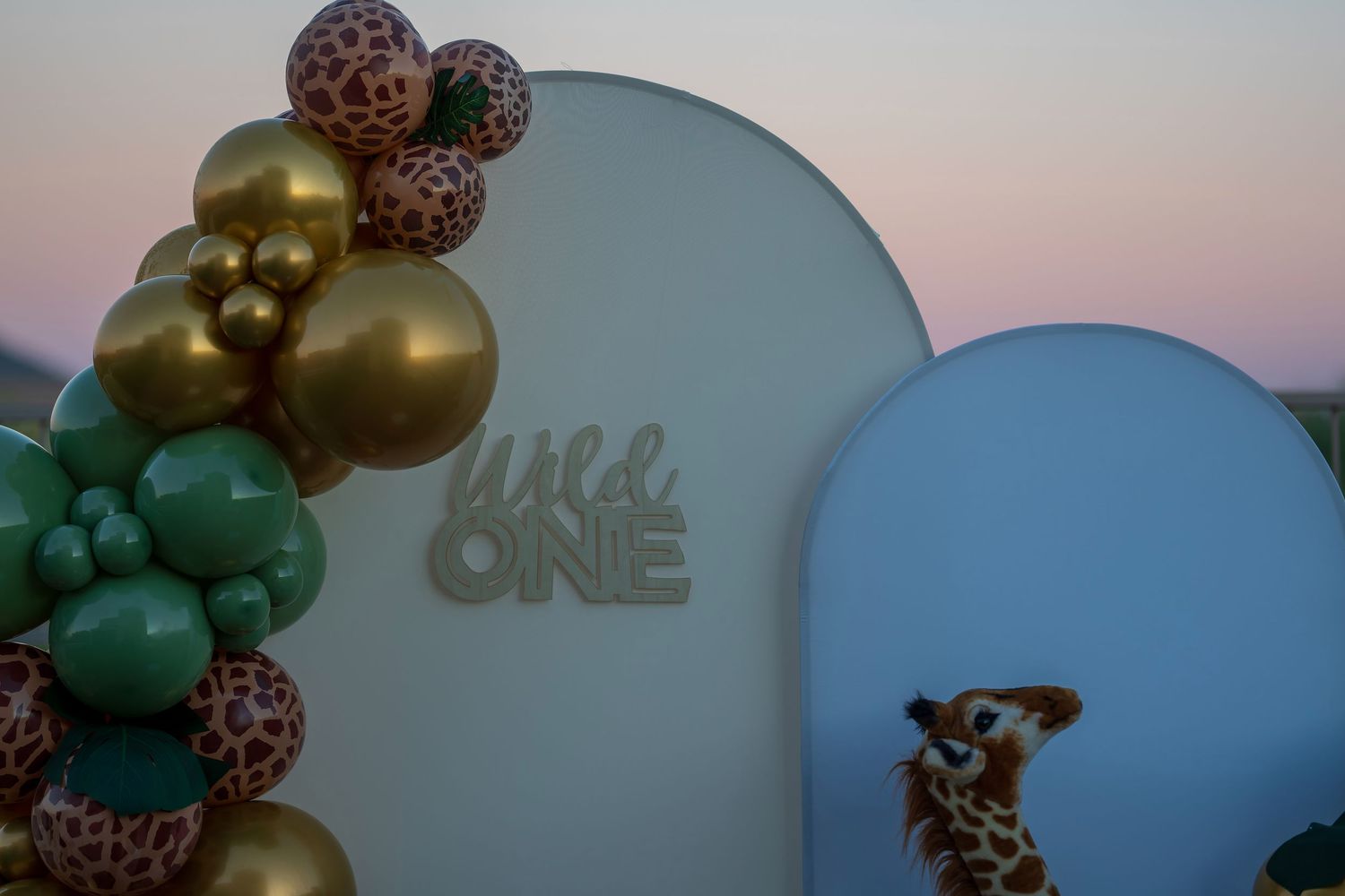 White and gold balloon arch with safari-themed decorative elements.