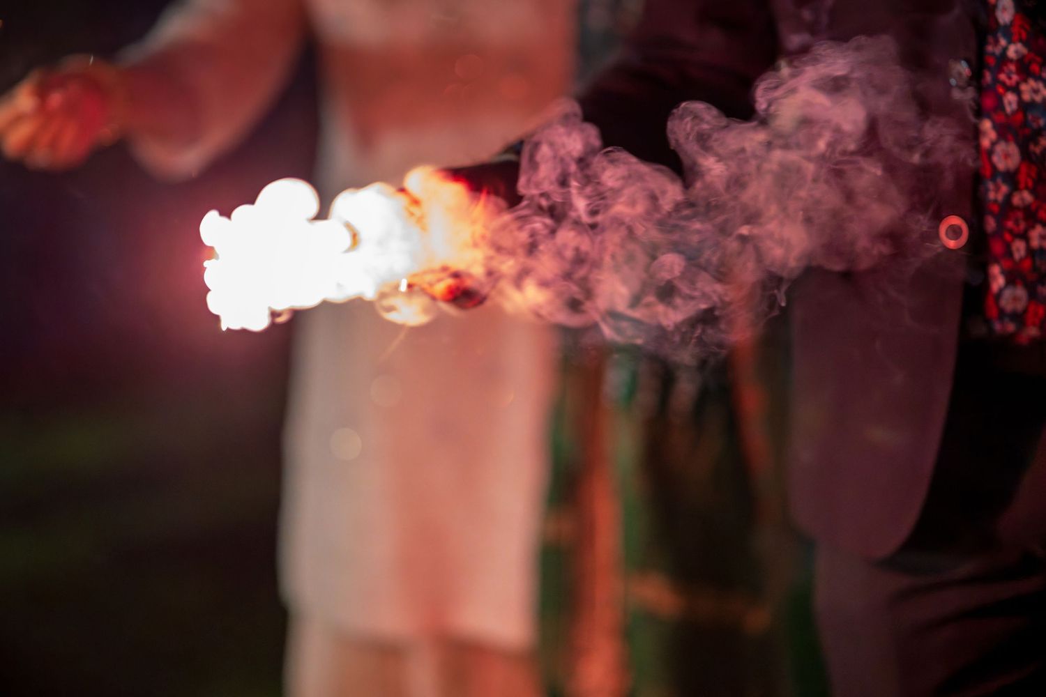 A close-up shot of a sparkler emitting smoke and light against a dark background.