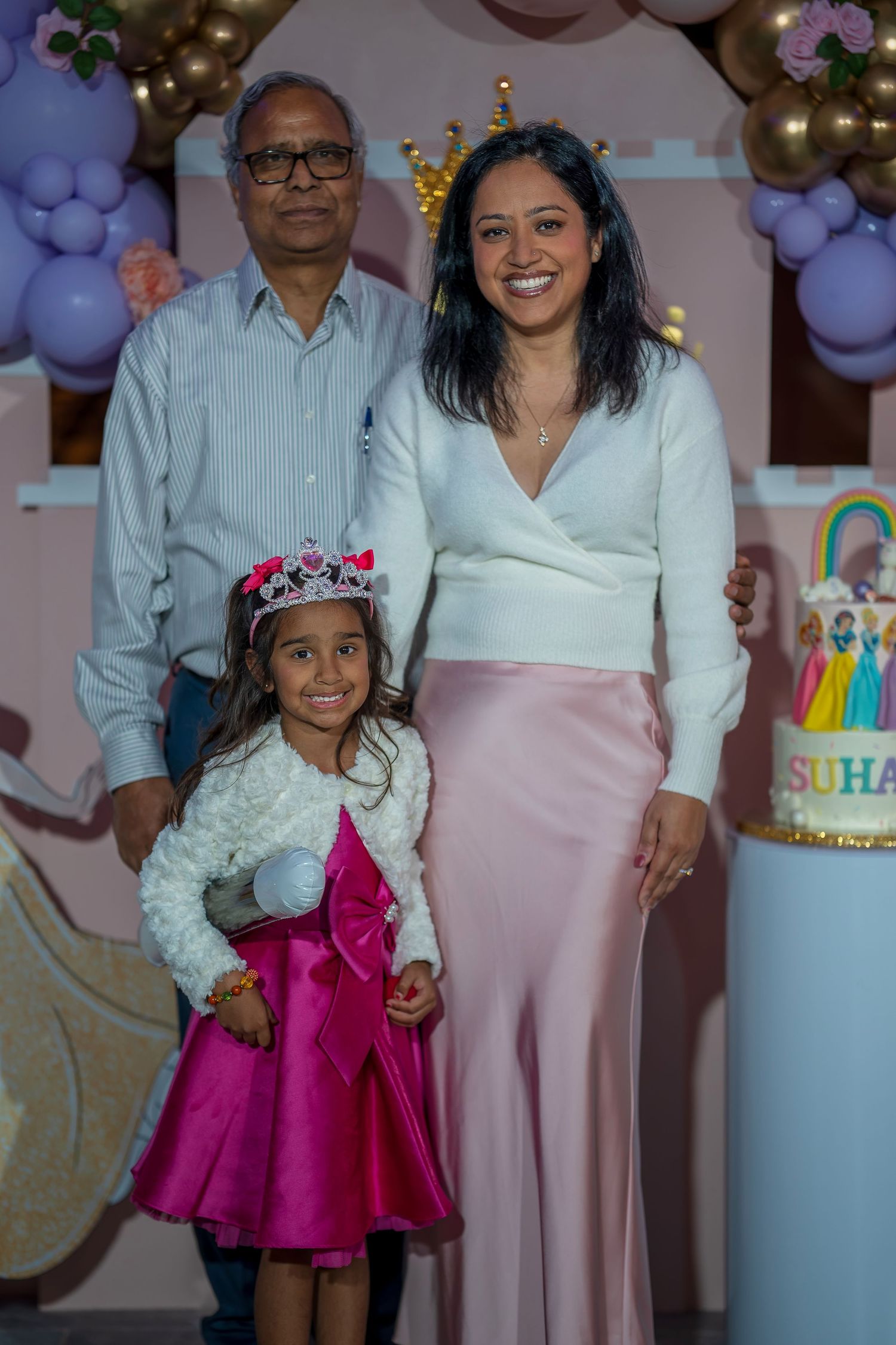 A birthday party scene with a decorated cake, purple balloons, and rainbow decorations.