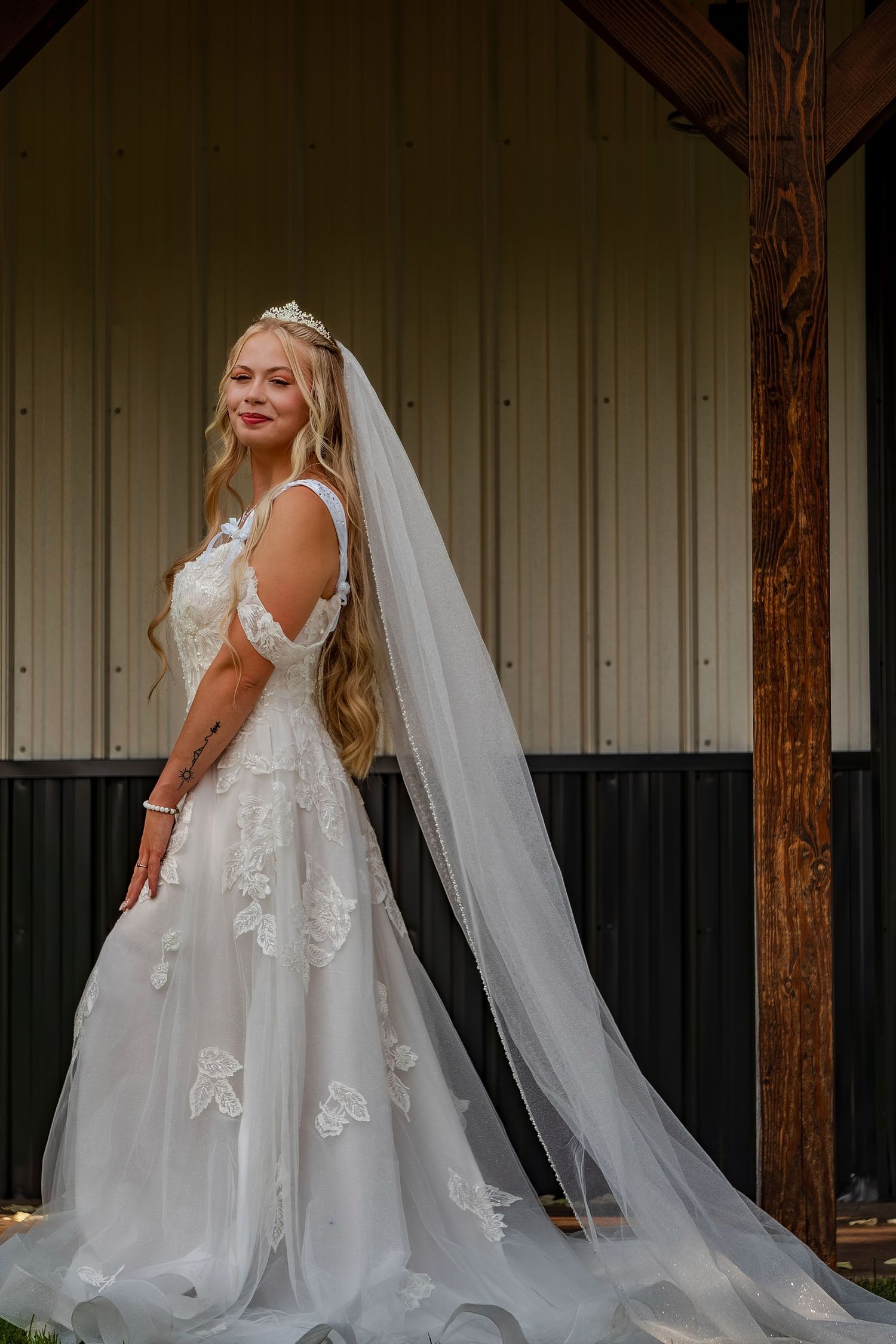 Side view of a bride in an elegant white wedding gown with lace details and flowing veil.