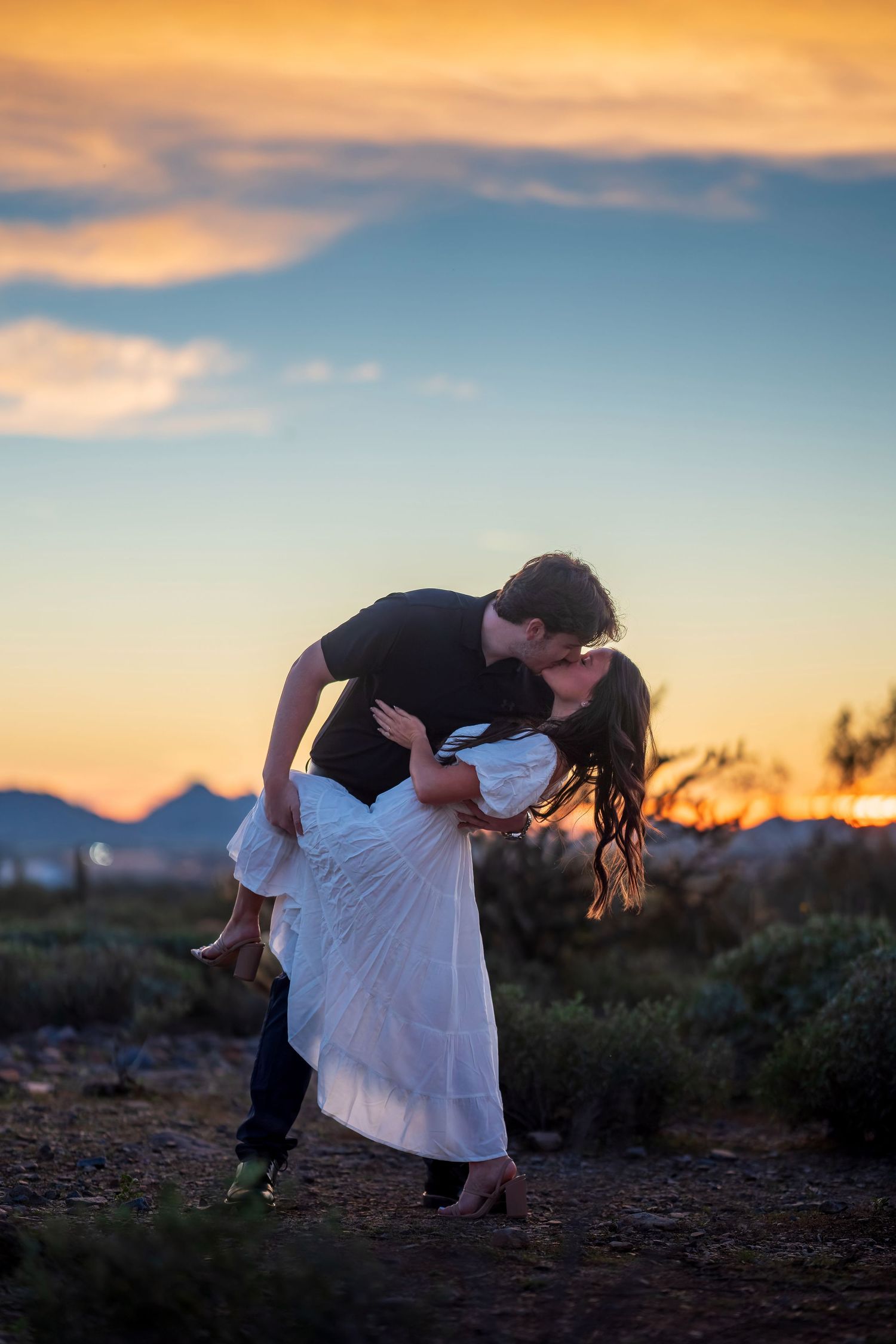 A dramatic dip pose silhouetted against a desert sunset sky.