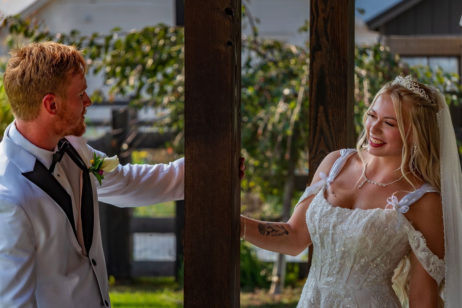 Candid wedding moment between couple under wooden pergola.