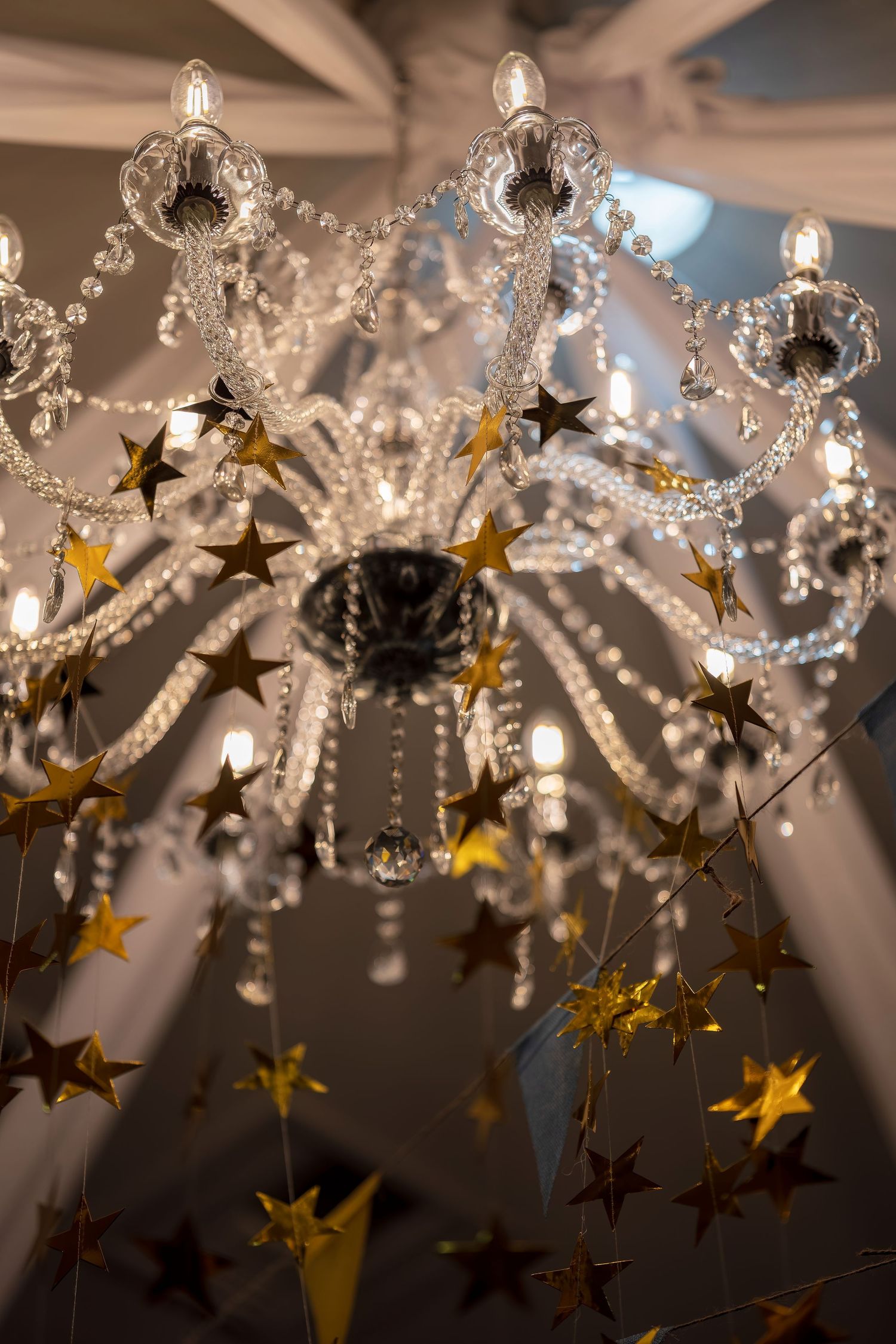 Crystal chandelier decorated with golden stars creating an elegant party atmosphere.