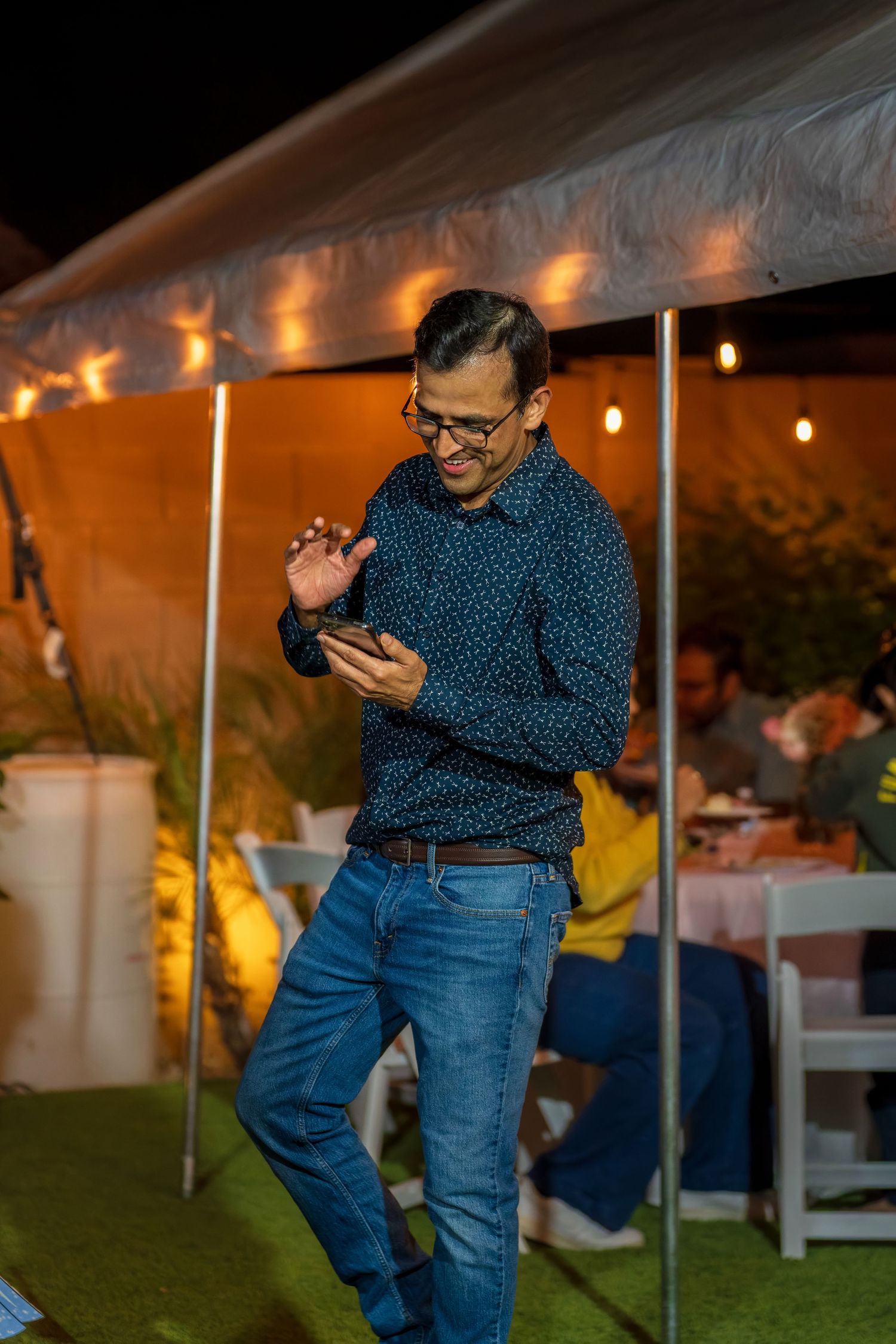 Guest dancing under string lights at an outdoor evening celebration.