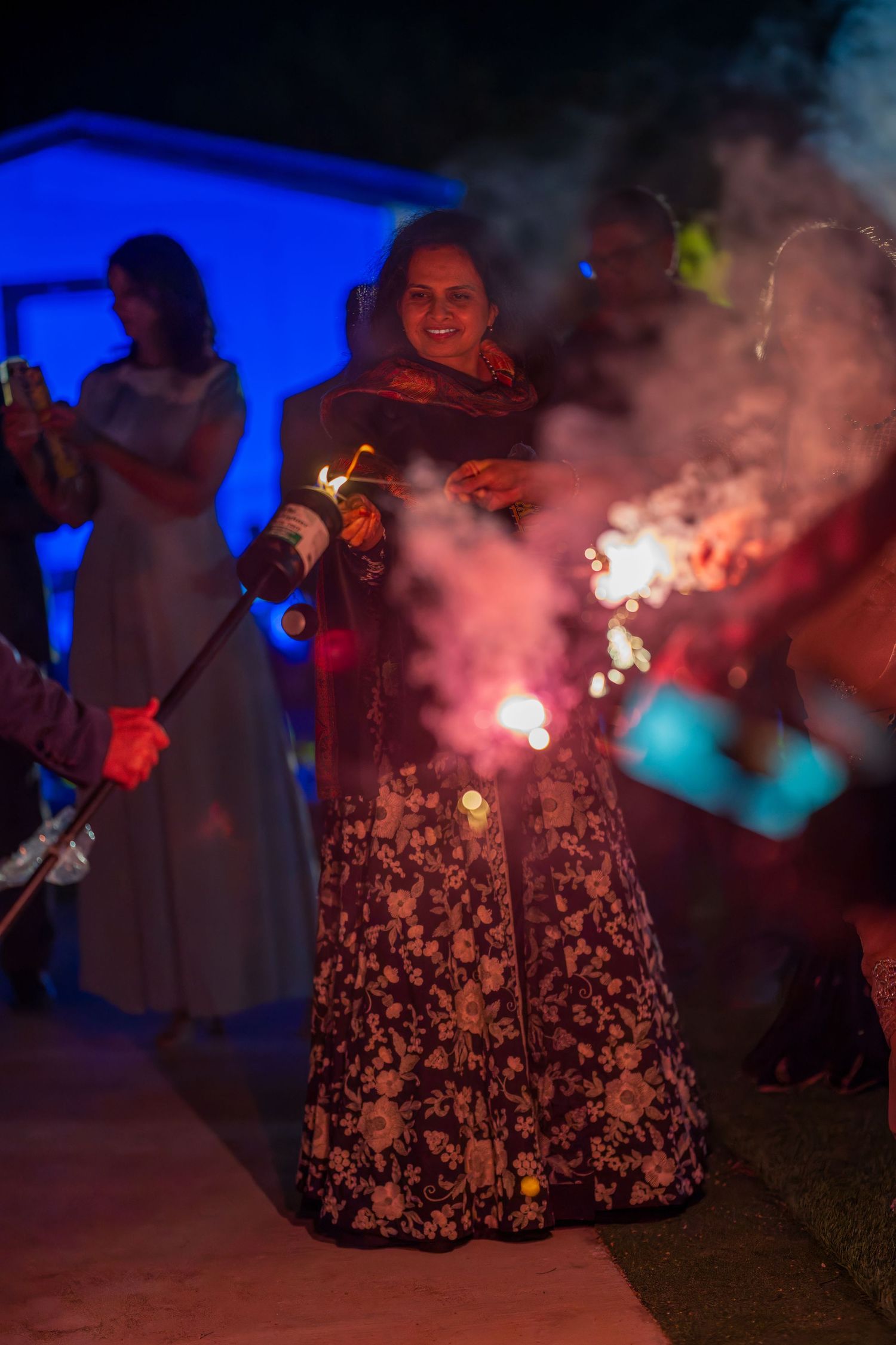 Colorful smoke and sparklers create a festive atmosphere against blue lighting.