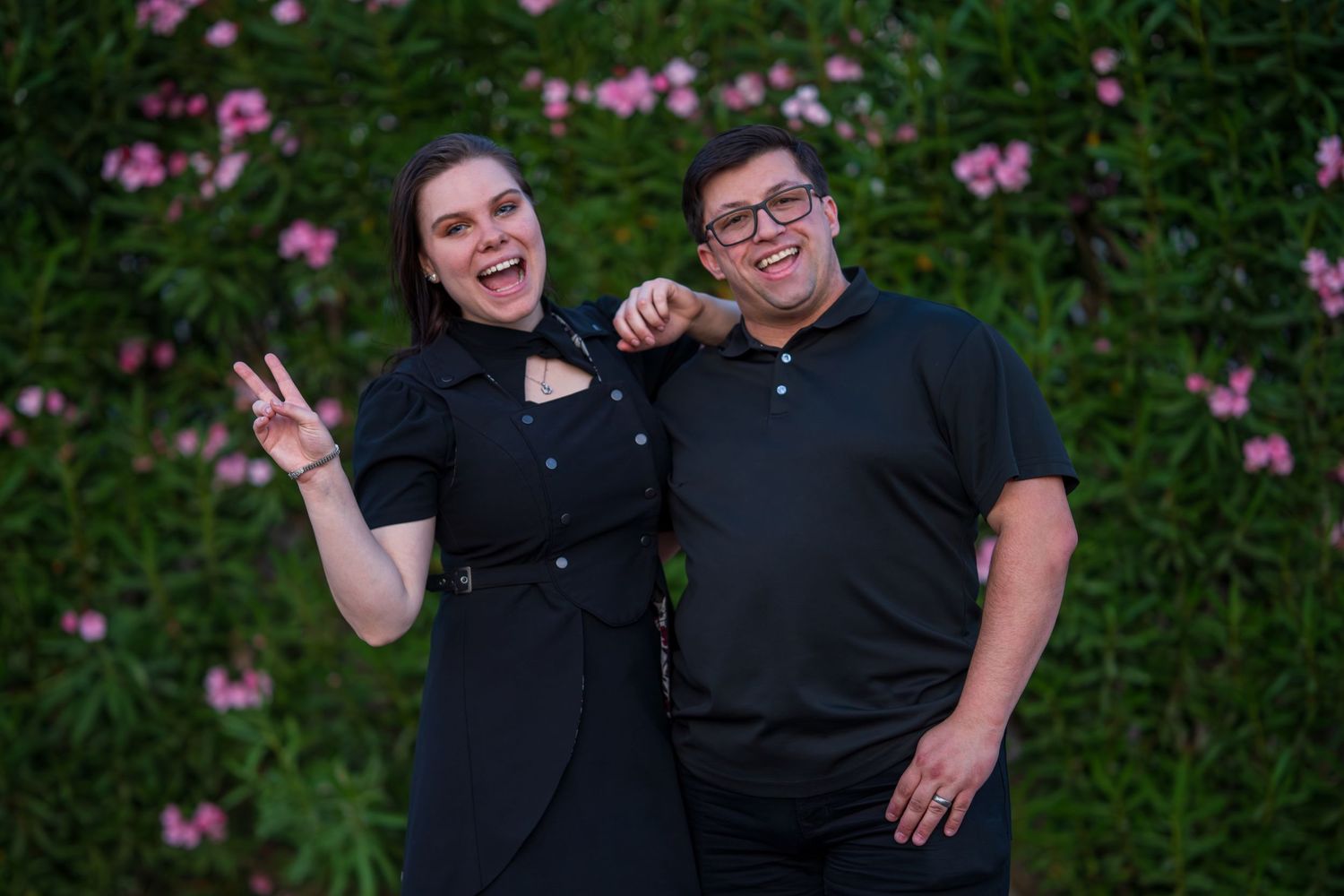 J and J taking casual photos in front of a garden setting.