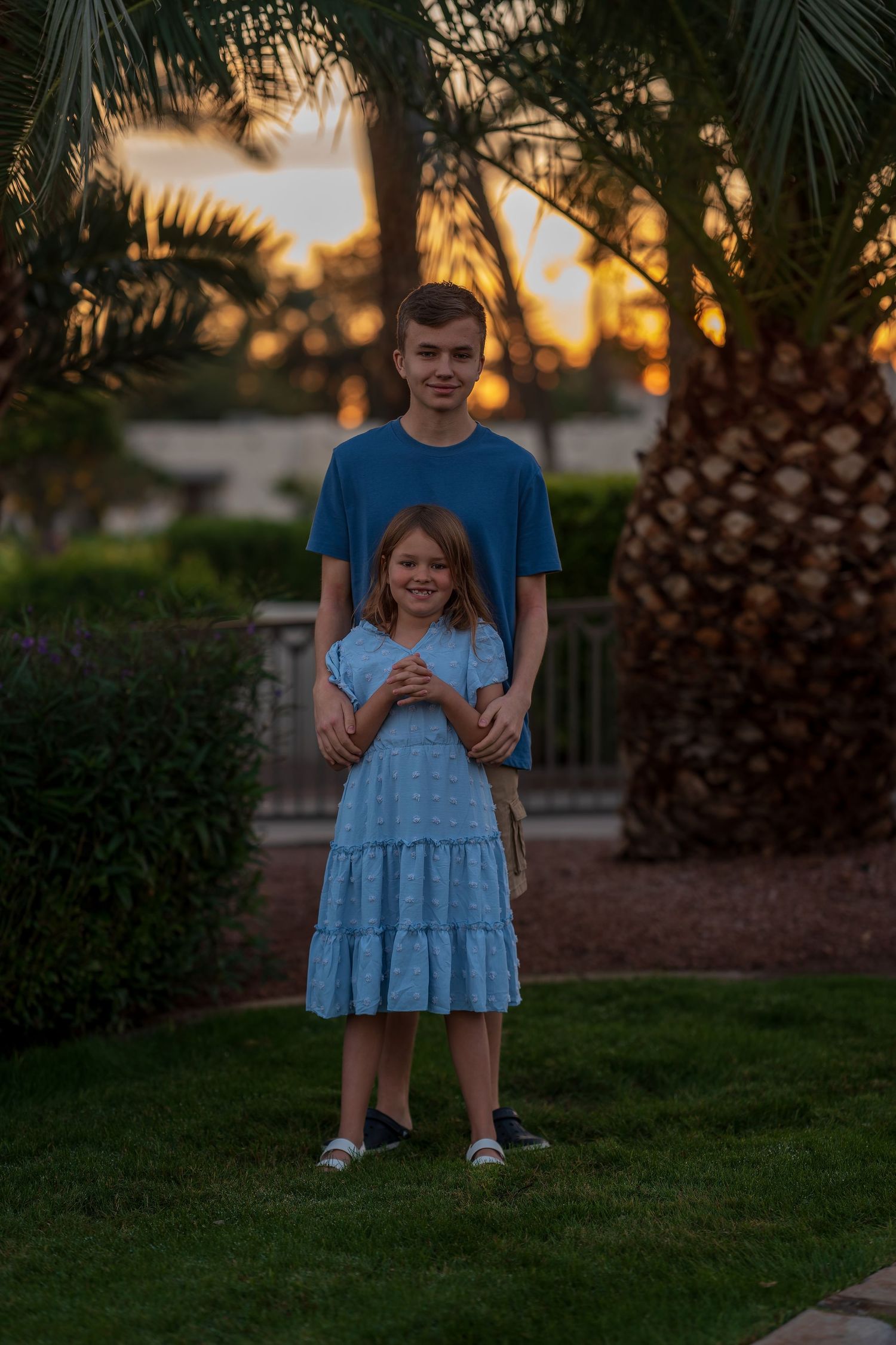 Family members pose together at sunset with palm trees in the background.