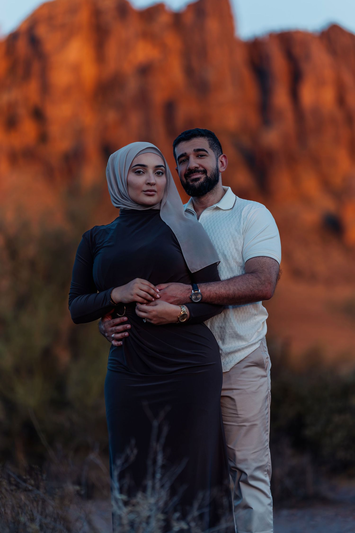 Couple sharing intimate moments against red rock formations at sunset.