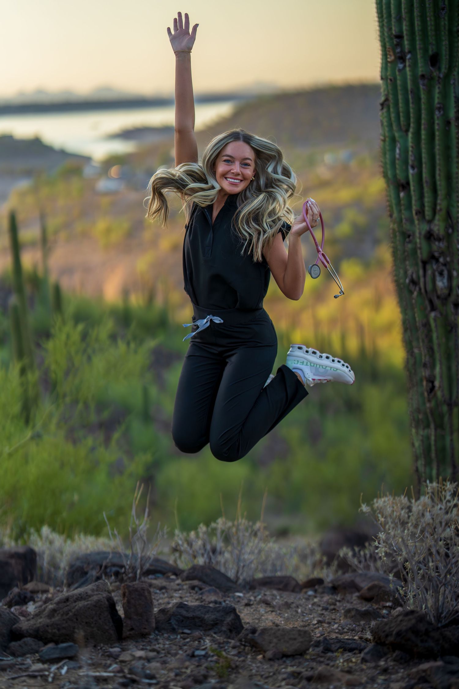Energetic leap captured against desert sunset with towering saguaro cacti in background.