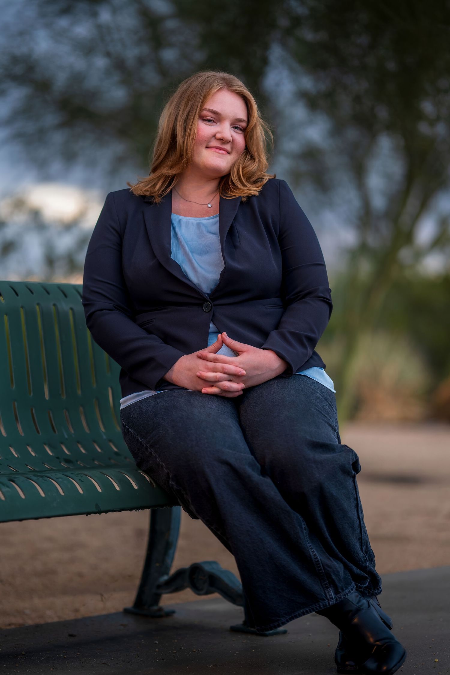Relaxed outdoor portrait session on a park bench in professional business wear.