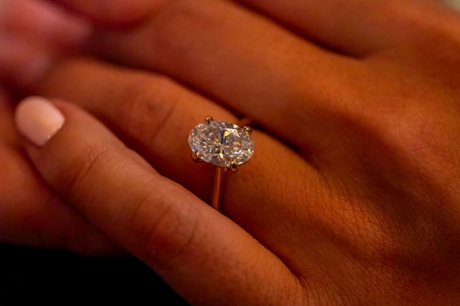 Detailed view of a large diamond ring on someone's finger.