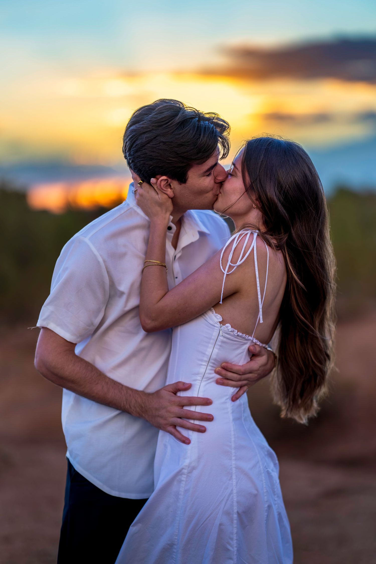 A tender embrace captured during a desert engagement photoshoot at sunset.