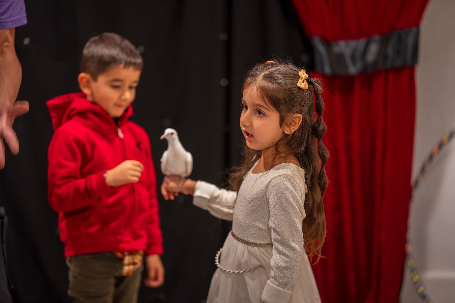 Children gather around to observe a white dove during a performance.