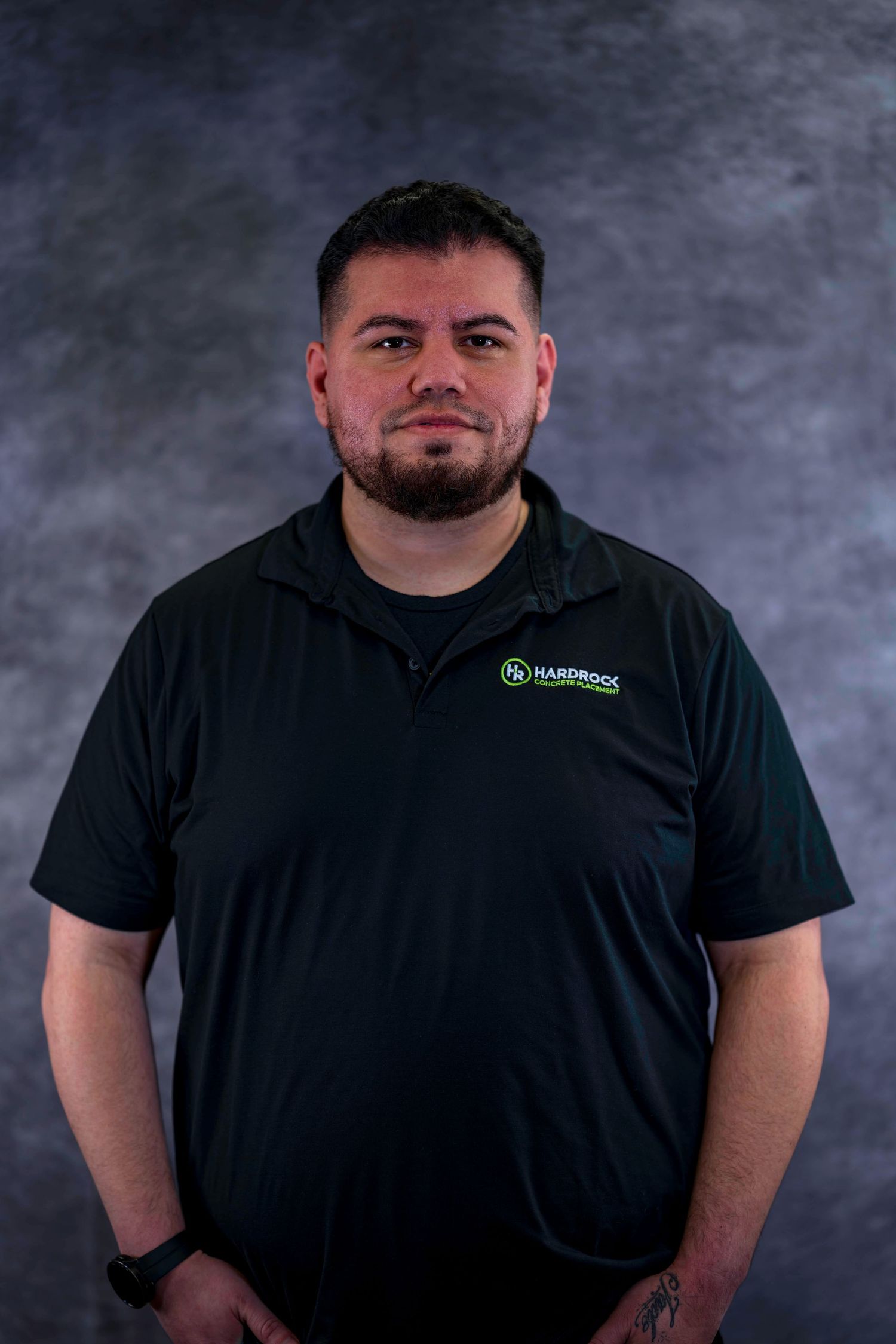 Staff photo of person in black company polo shirt against mottled gray backdrop.
