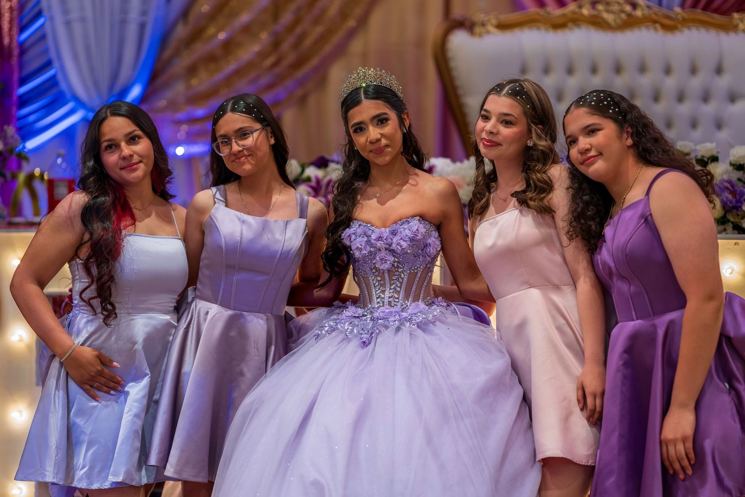 Quinceañera girl in lavender ball gown poses with four friends in purple and silver dresses.