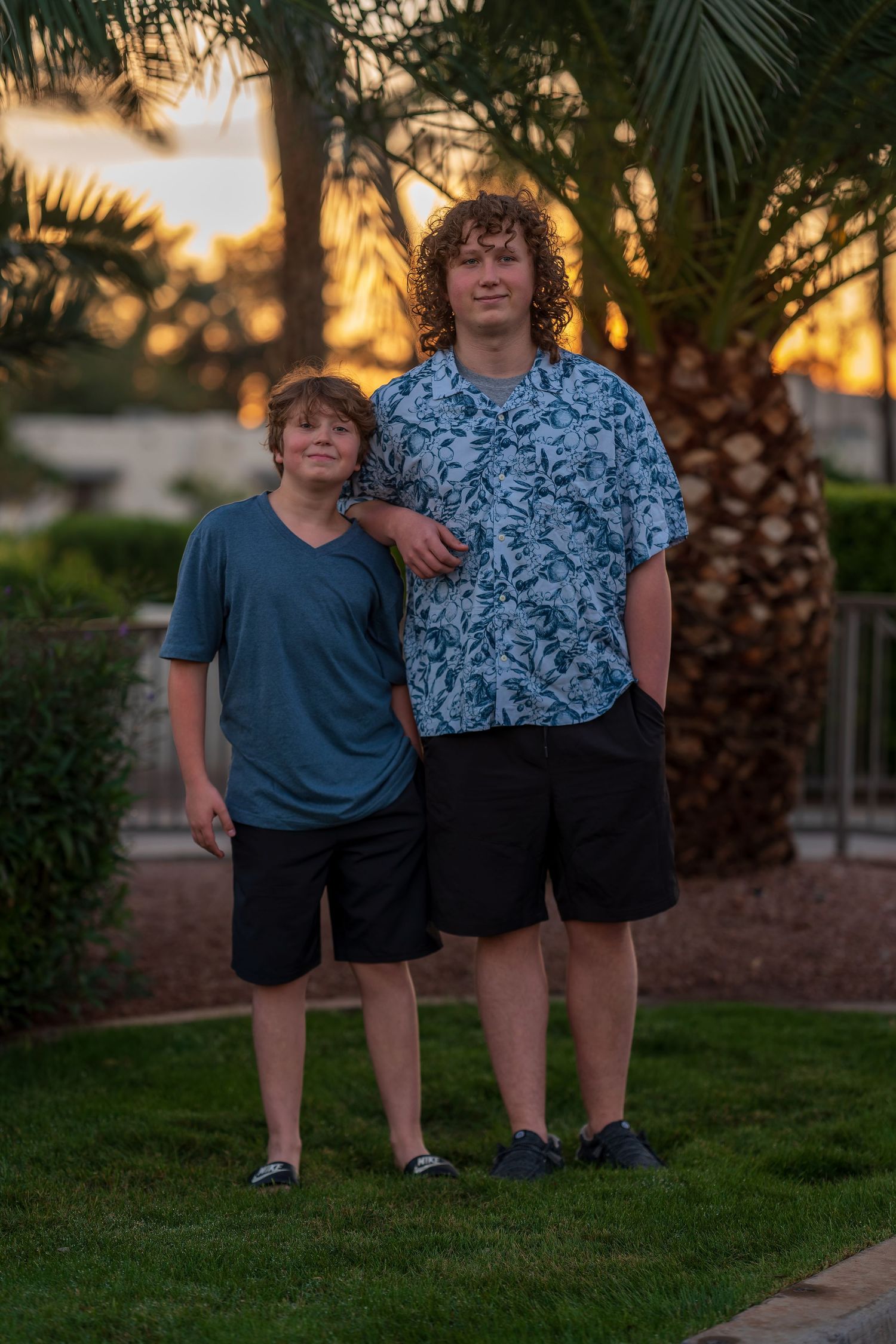 Family members pose together outdoors at sunset near palm trees.