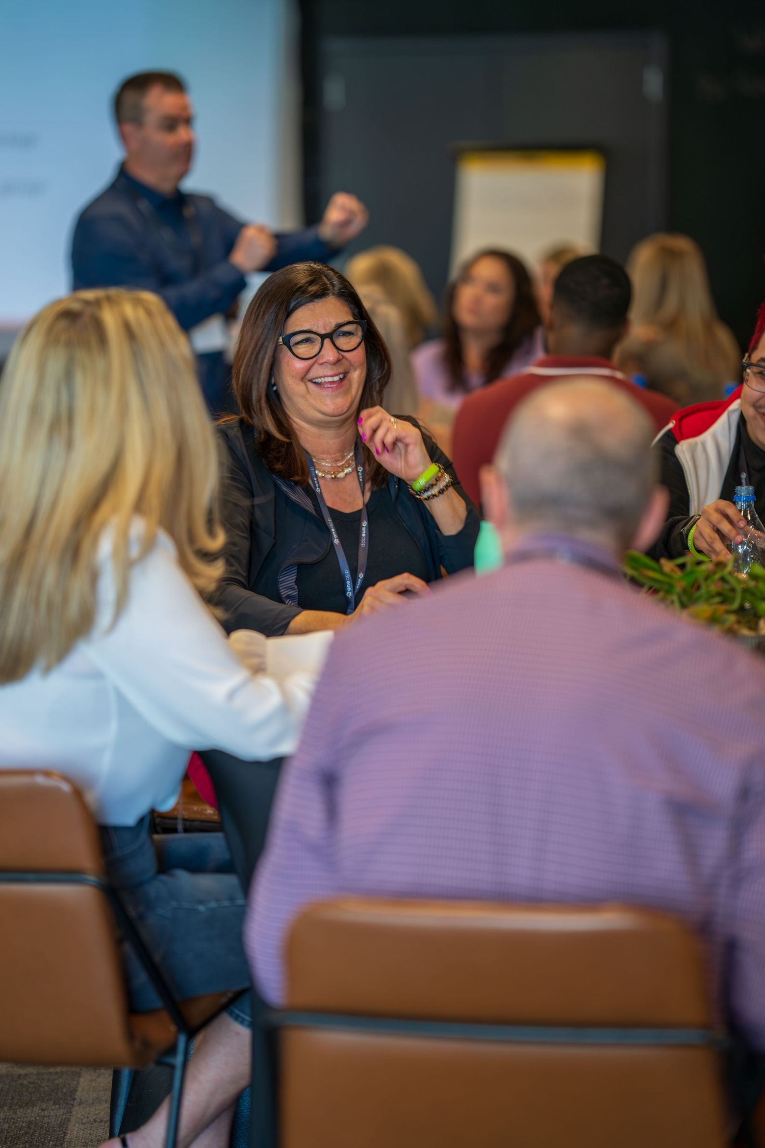 Business meeting participants engage in discussion around conference table.