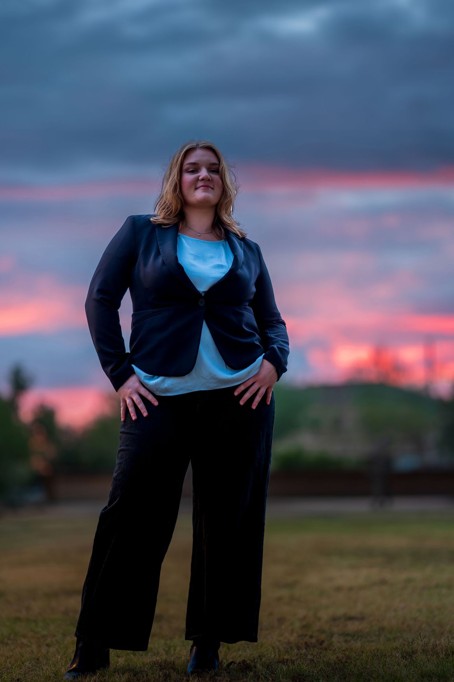 Professional photoshoot in an open field during blue hour with vibrant sunset colors.
