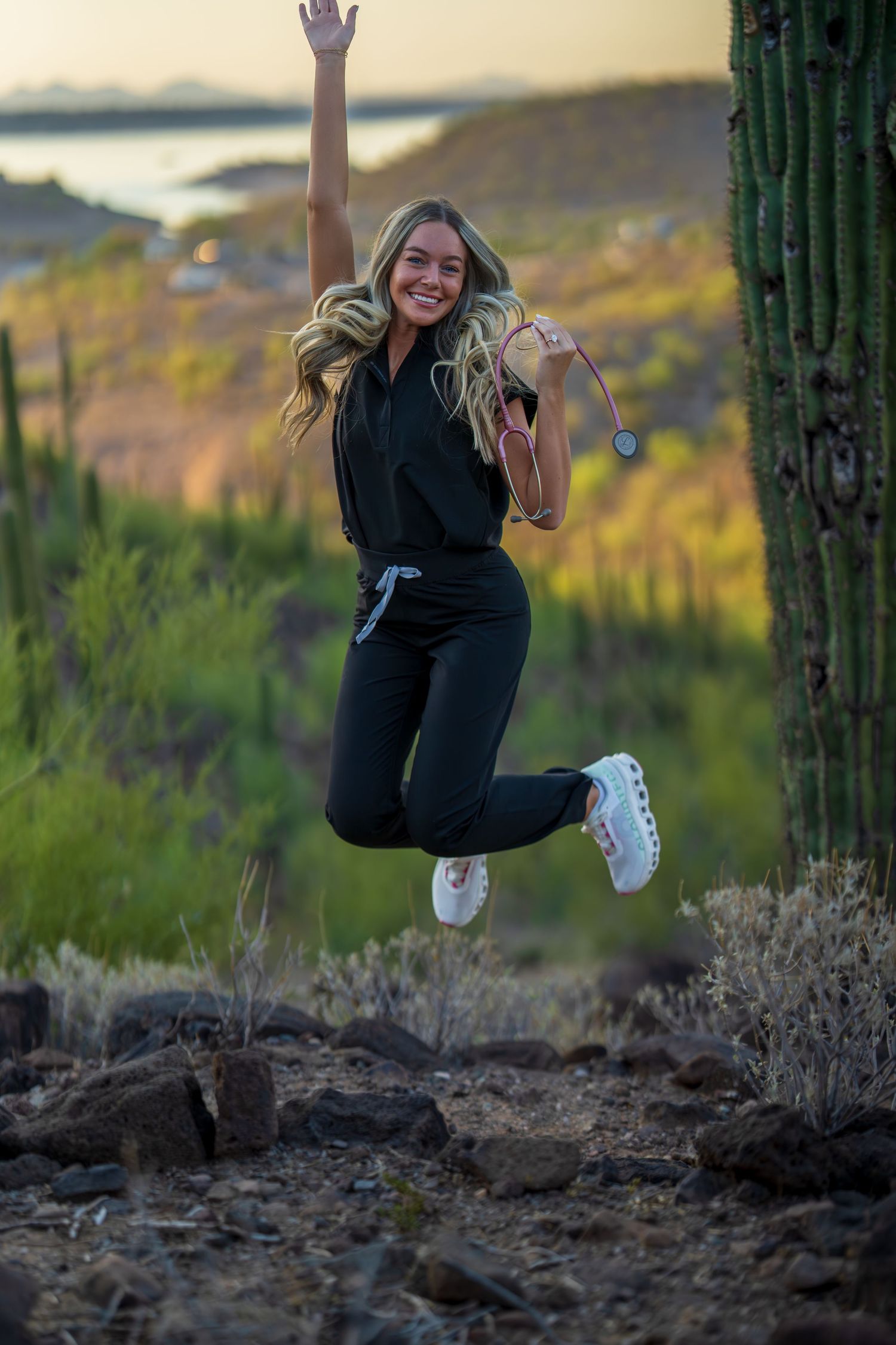 Dynamic action shot of medical professional jumping in desert landscape with saguaro cacti.