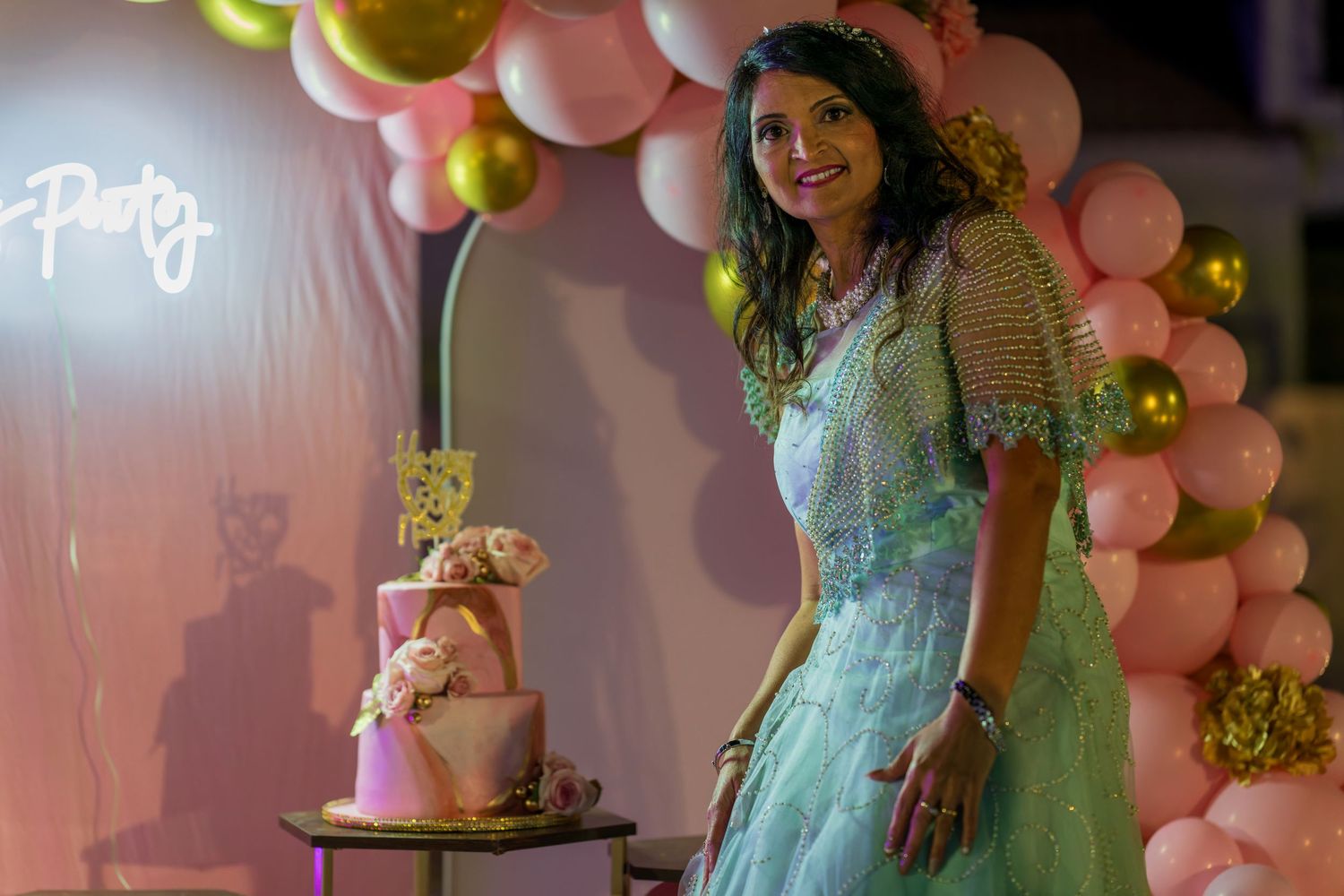 A celebration scene with pink balloons and decorative lighting.