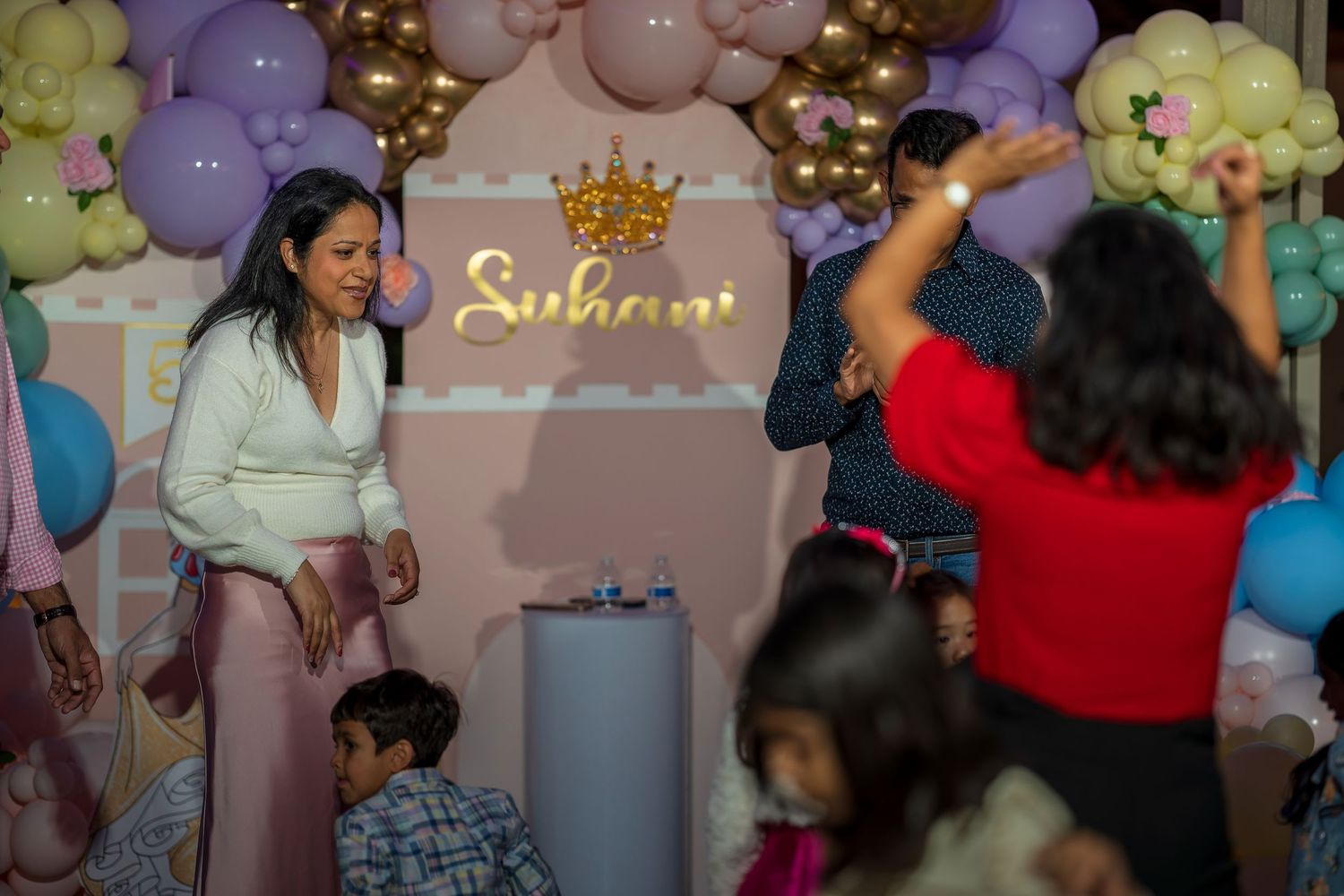 Festive celebration with balloon decorations and people dancing under ambient lighting.