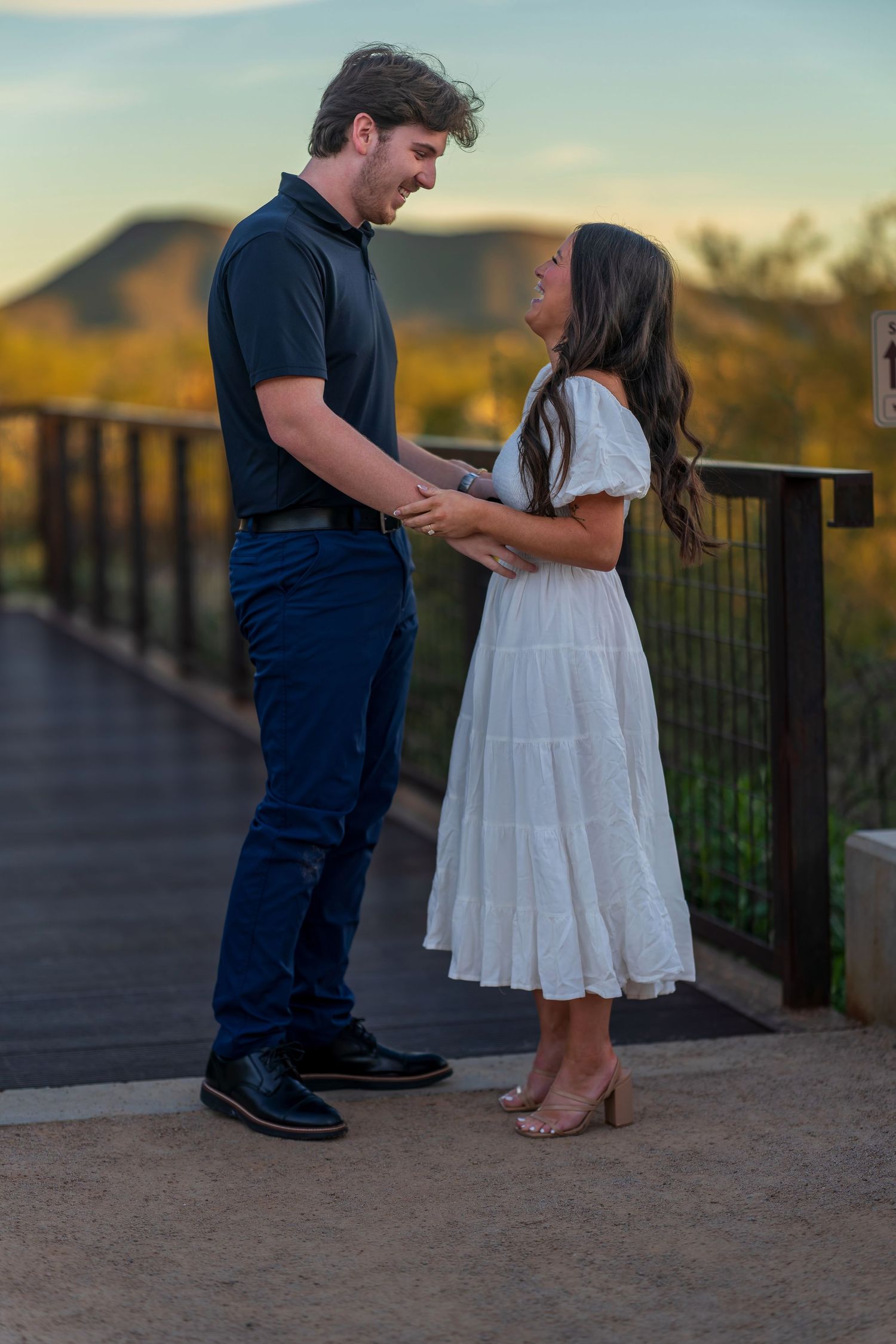 Two people share a romantic moment on an outdoor deck with scenic mountain views.