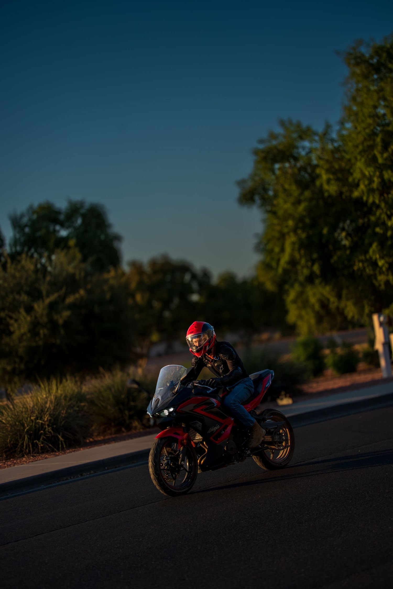 Red motorcycle parked on road during sunset with dramatic shadows.
