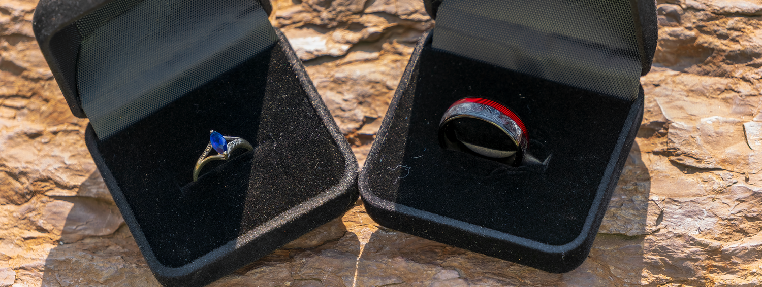 Collection of wedding rings and jewelry displayed on dark surfaces.