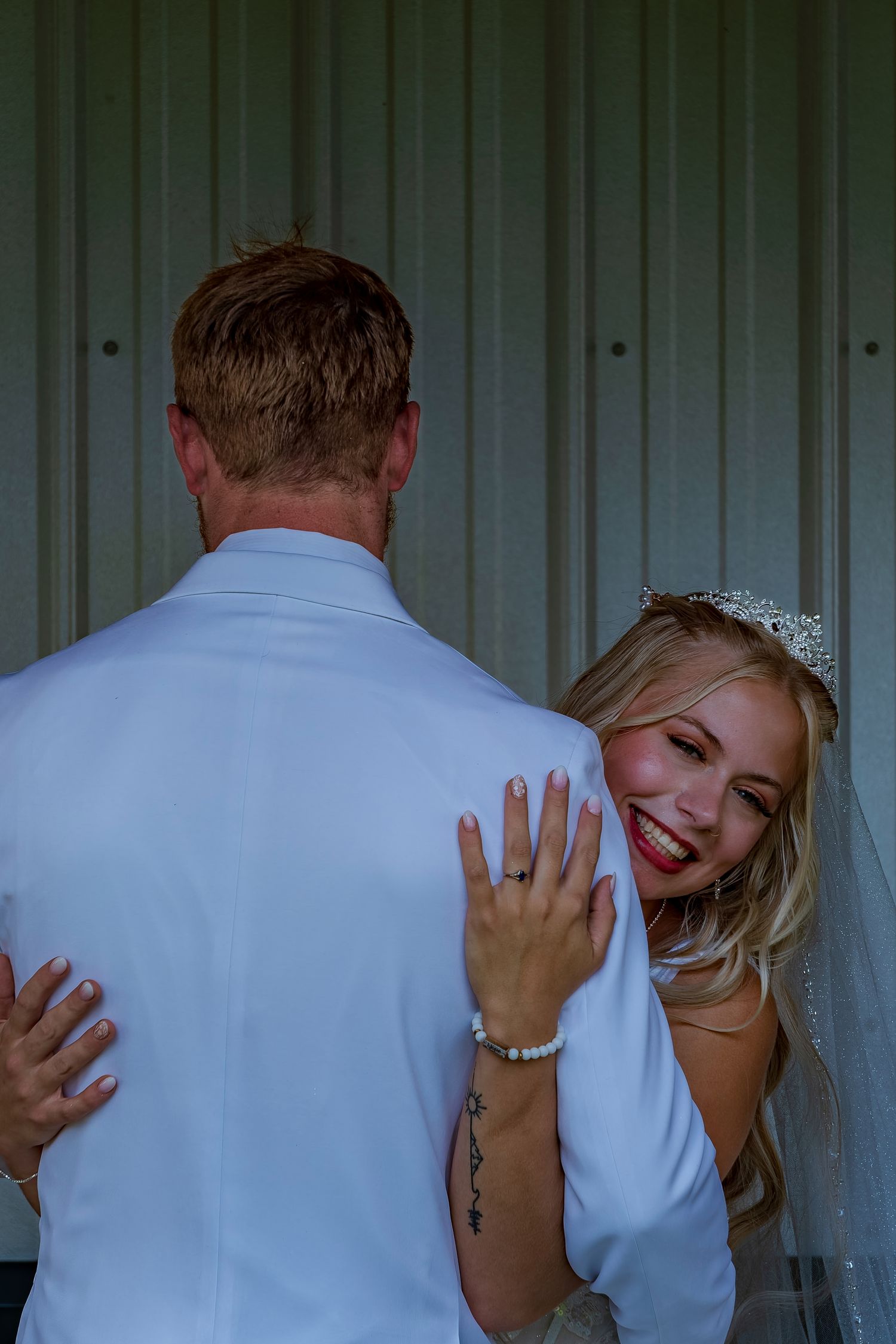 Intimate wedding photos showing tender moments between newlyweds against a metal wall backdrop.