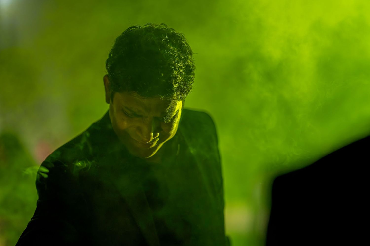 Figure silhouetted against green atmospheric lighting and smoke.