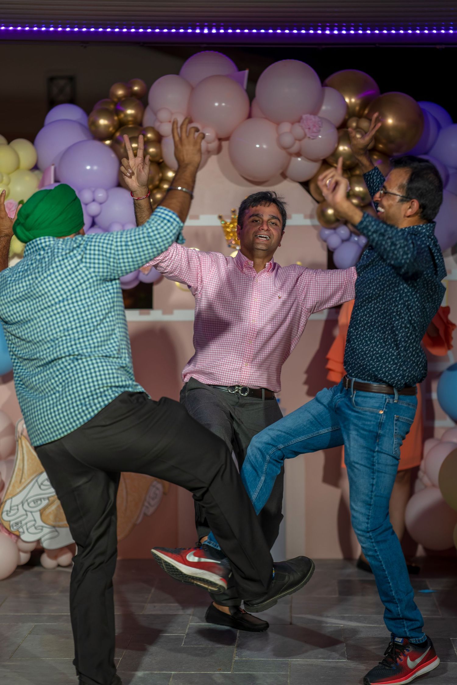 Dynamic dance moves performed at a celebration with balloon decorations and ambient lighting.
