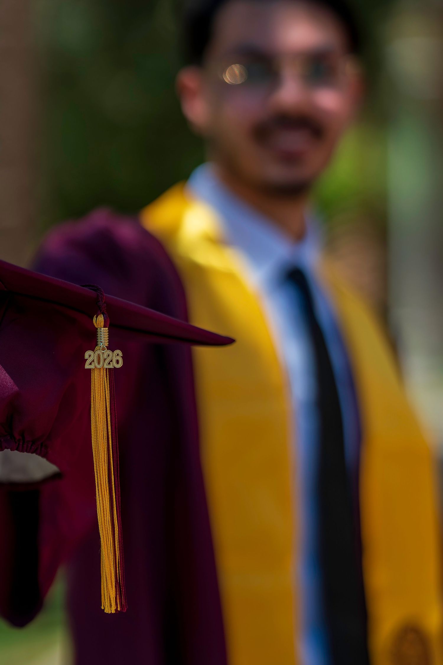 Close-up of a maroon 2026 graduation cap with gold tassel held by a graduate in commencement regalia.