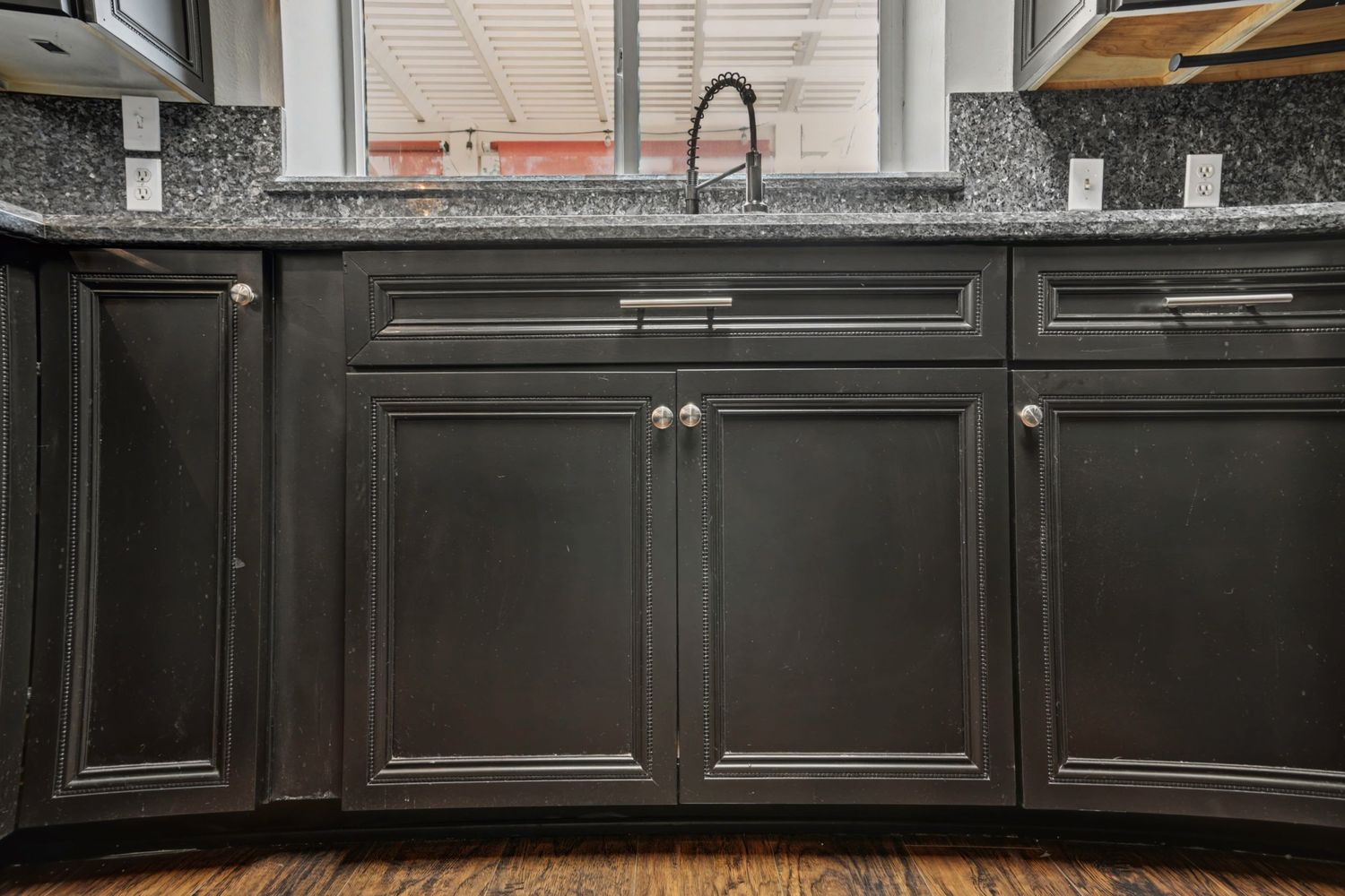 Dark espresso kitchen cabinets with granite countertop, modern hardware, and undermount sink.
