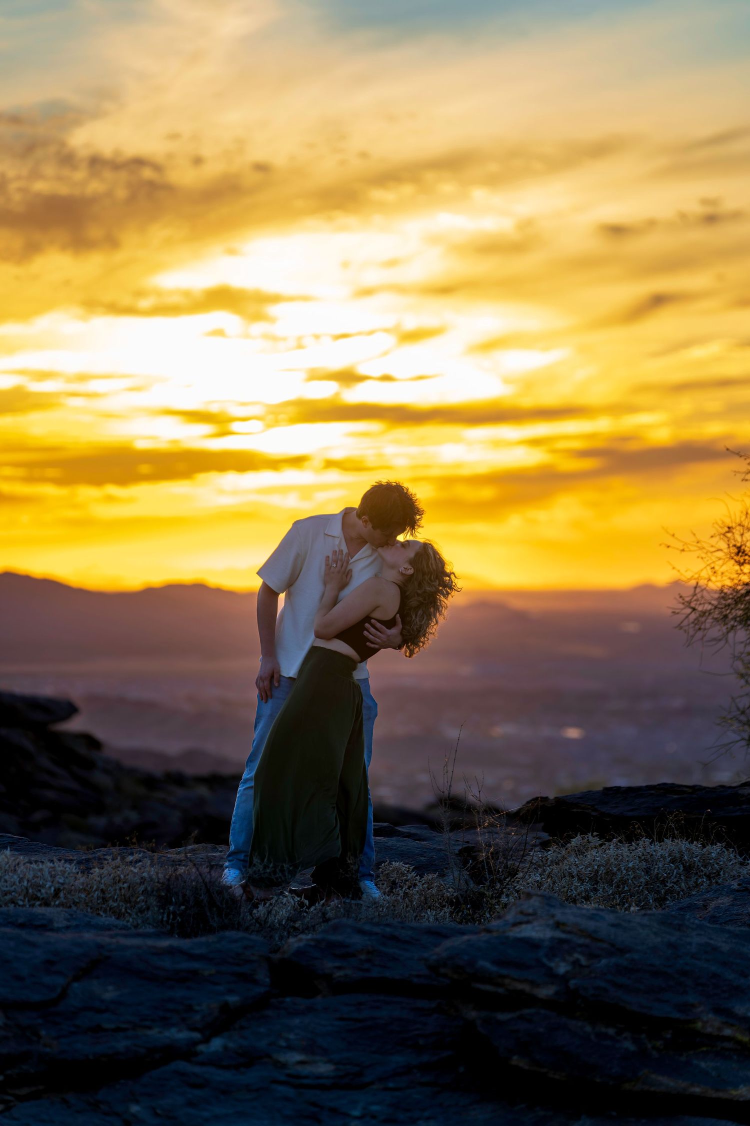 Couple sharing a passionate kiss silhouetted against a stunning golden desert sunset.