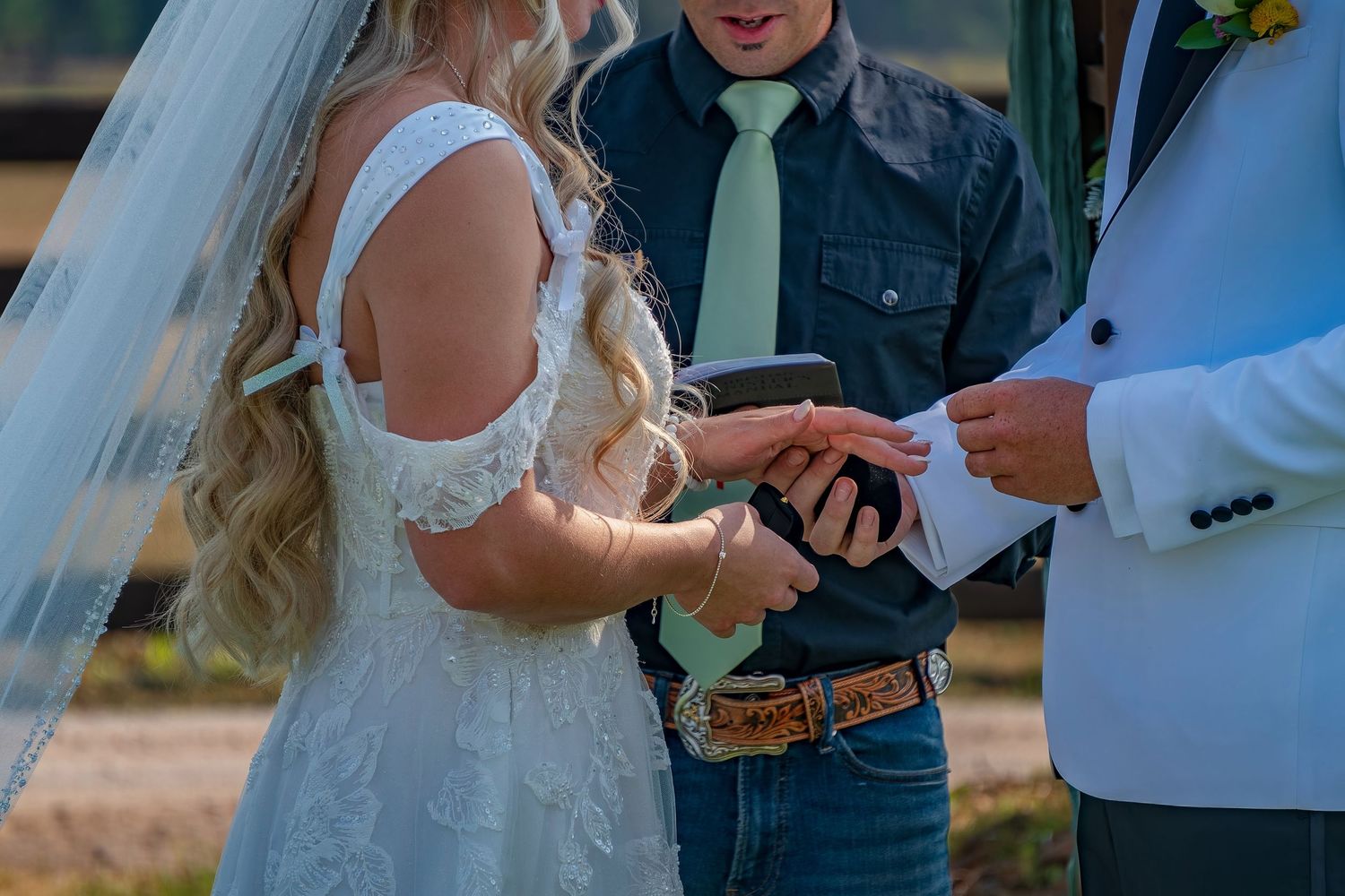 Wedding ceremony participants read from papers during an outdoor mountain celebration.