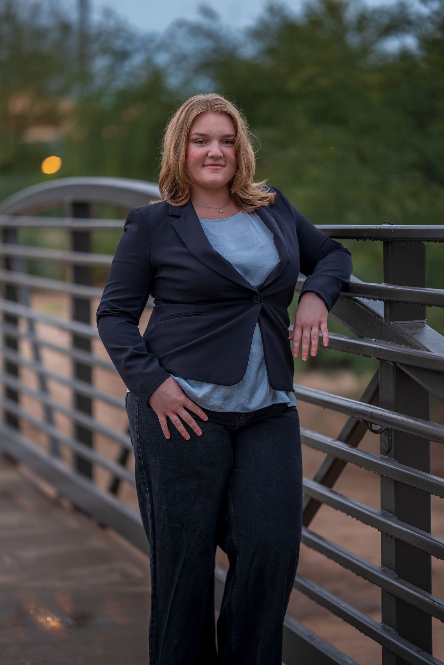 Professional portrait on bridge with evening lighting and railing details.