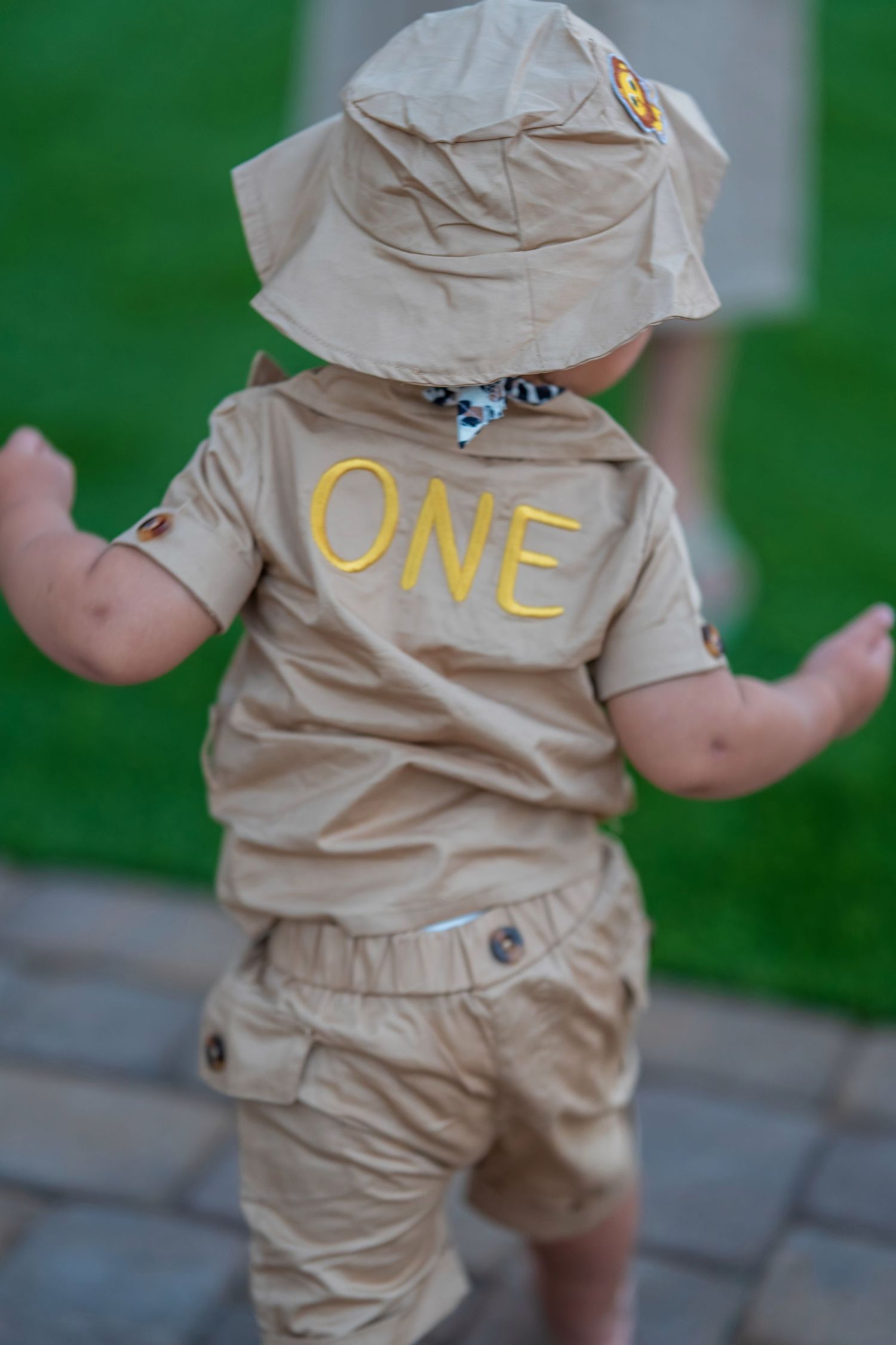 Rear view of toddler in safari explorer outfit with 'ONE' embroidered on back.
