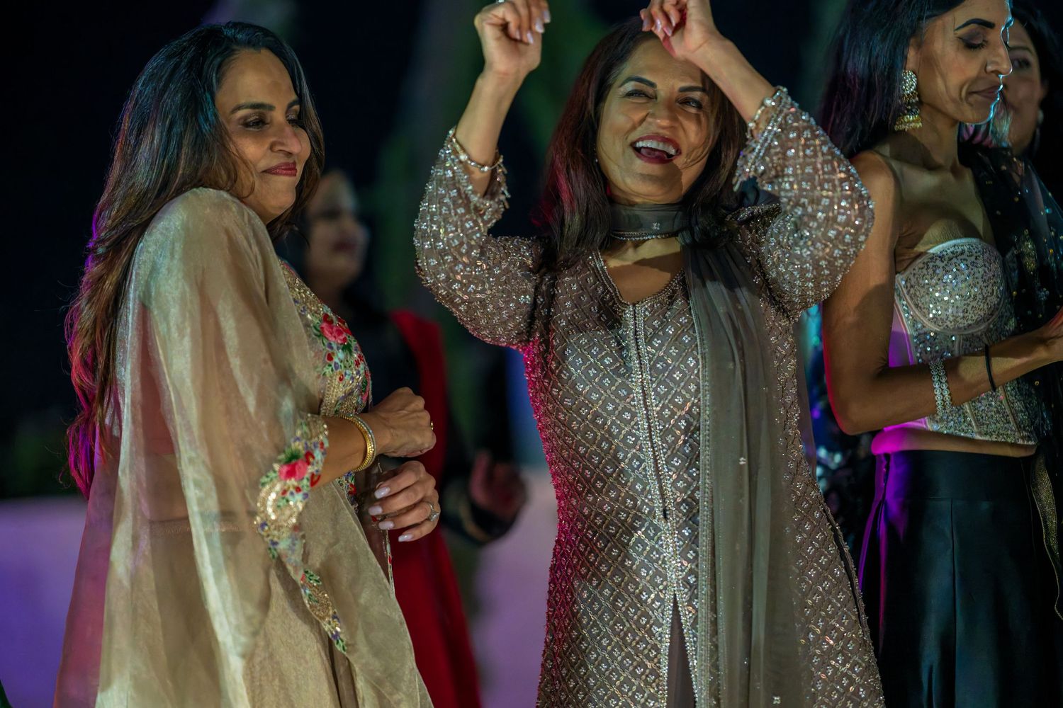 Women in traditional attire dancing and celebrating at a festive gathering.